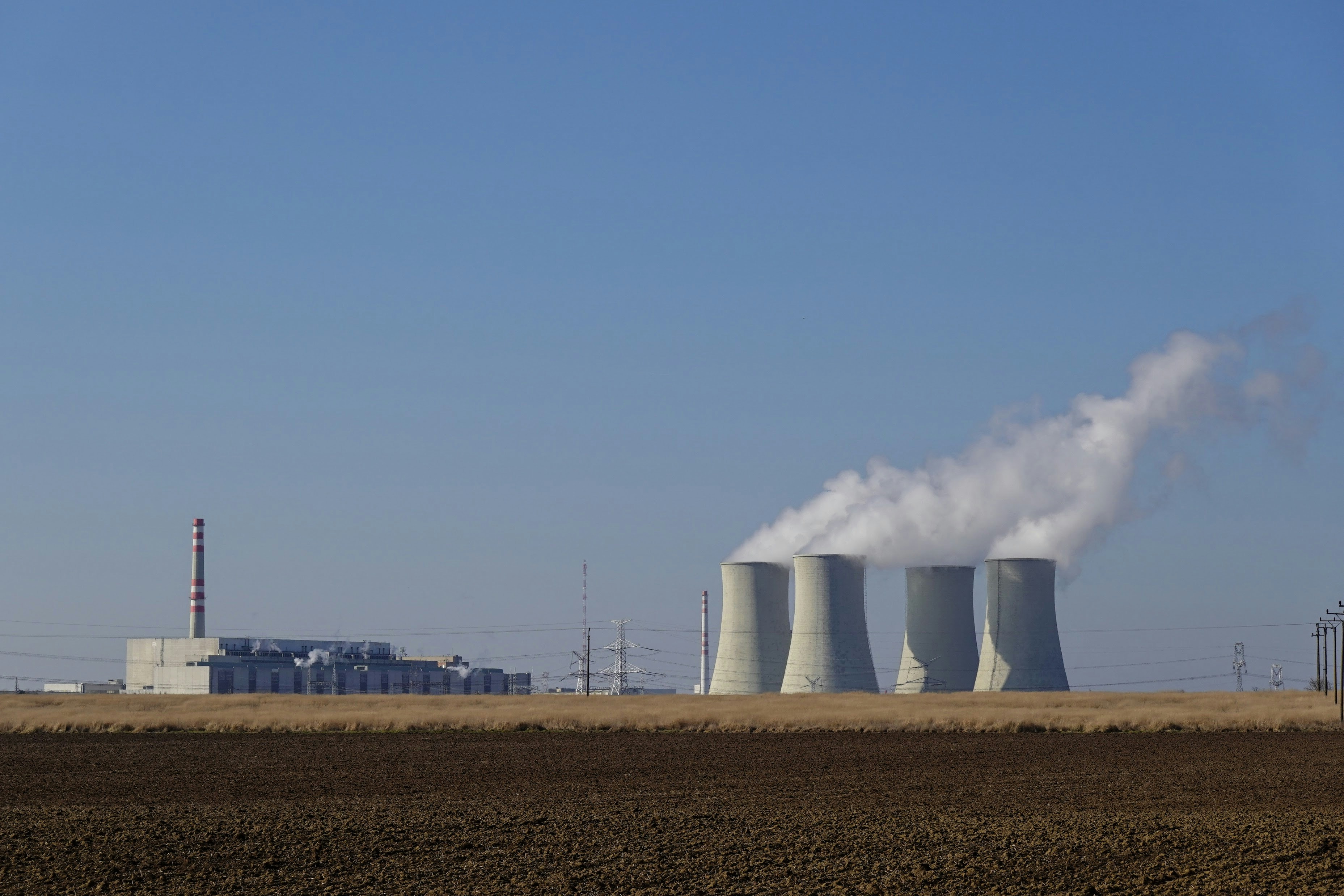 Industrial cooling towers emitting steam under a clear sky