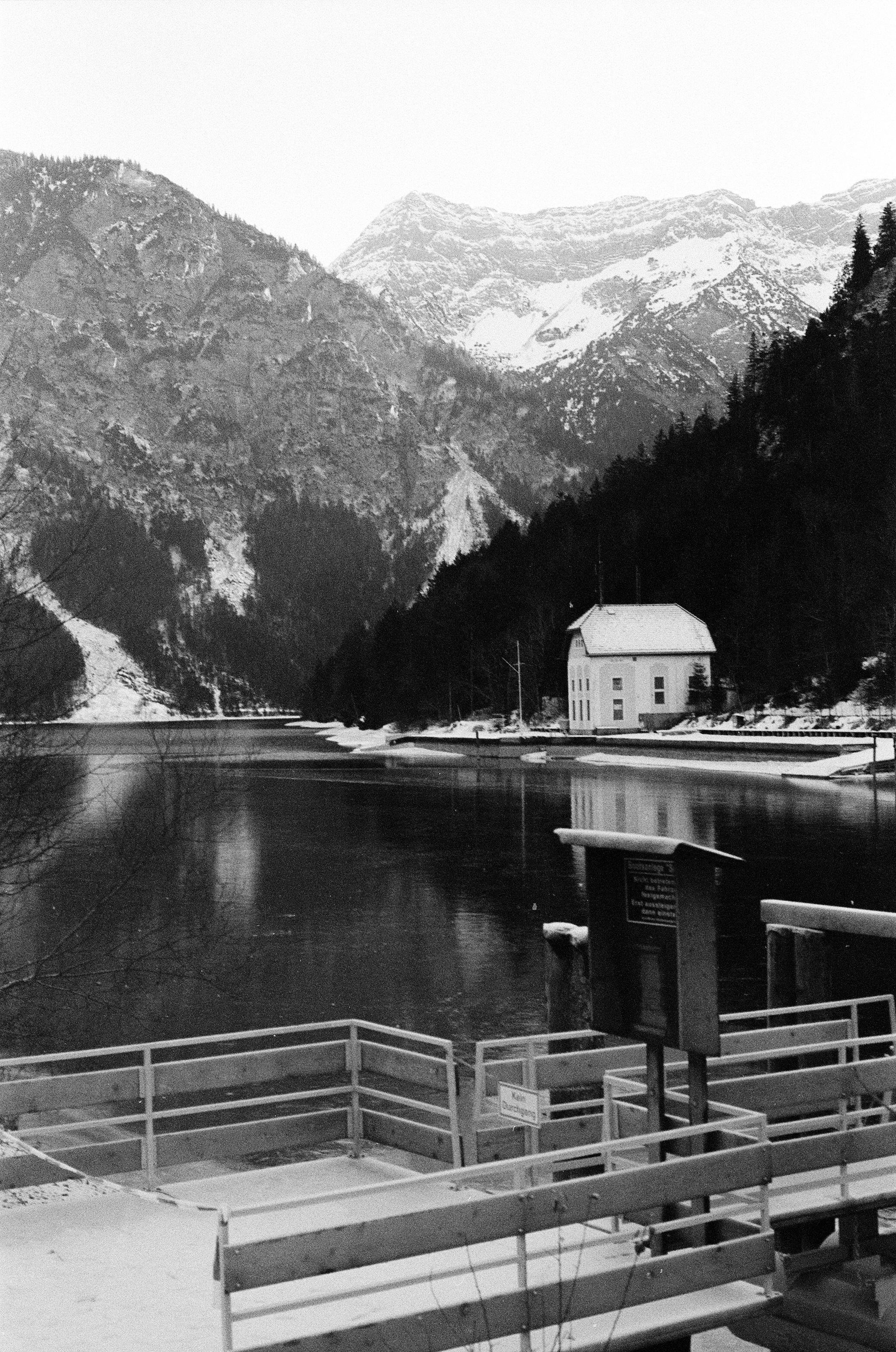 Bâtiment enneigé près d’un lac gelé et des montagnes