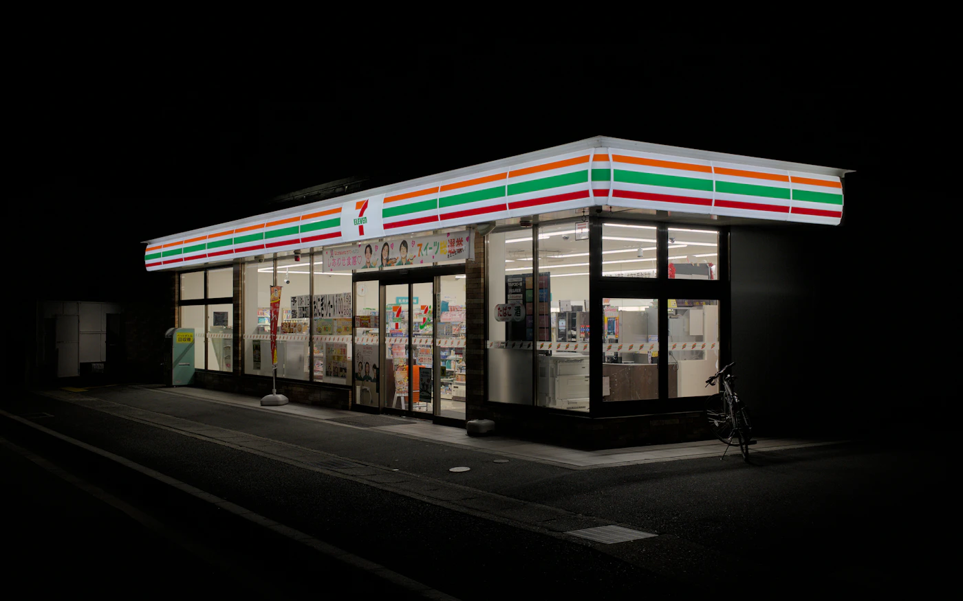 夜の京都、明るいコンビニの前の静かな道路