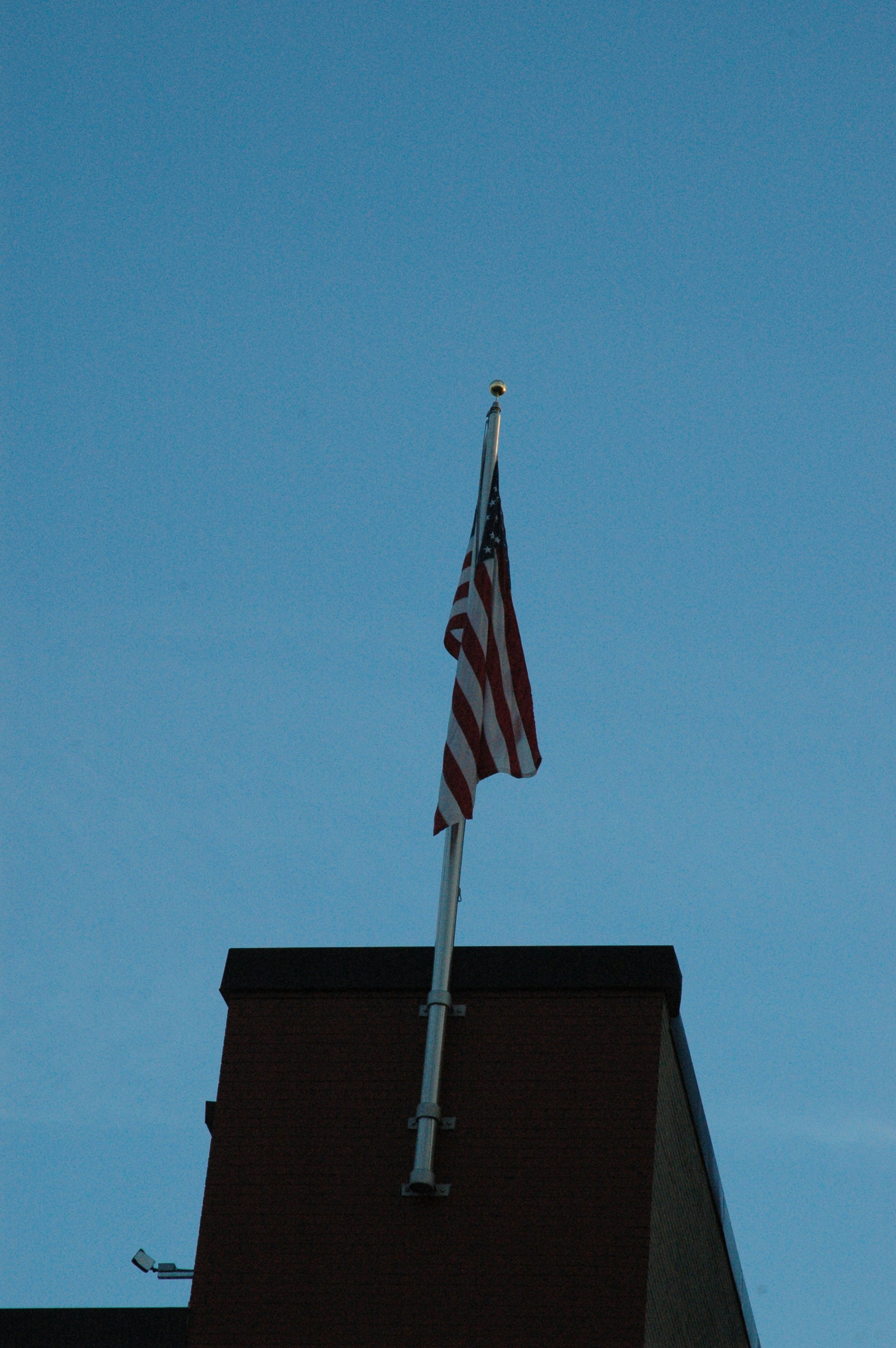Drapeau américain flottant sur un mât au sommet d’un bâtiment.