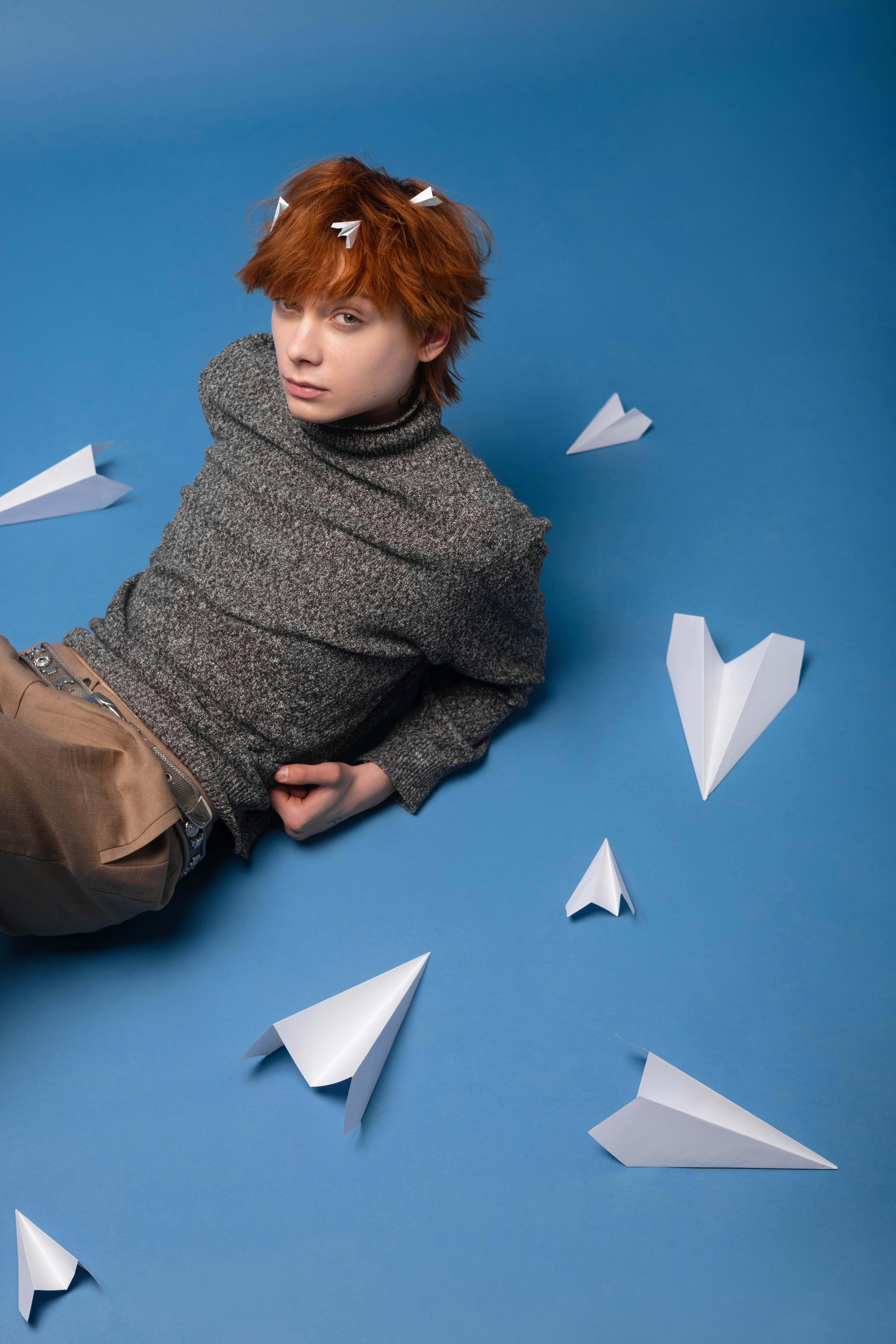 Young person with red hair and paper airplanes
