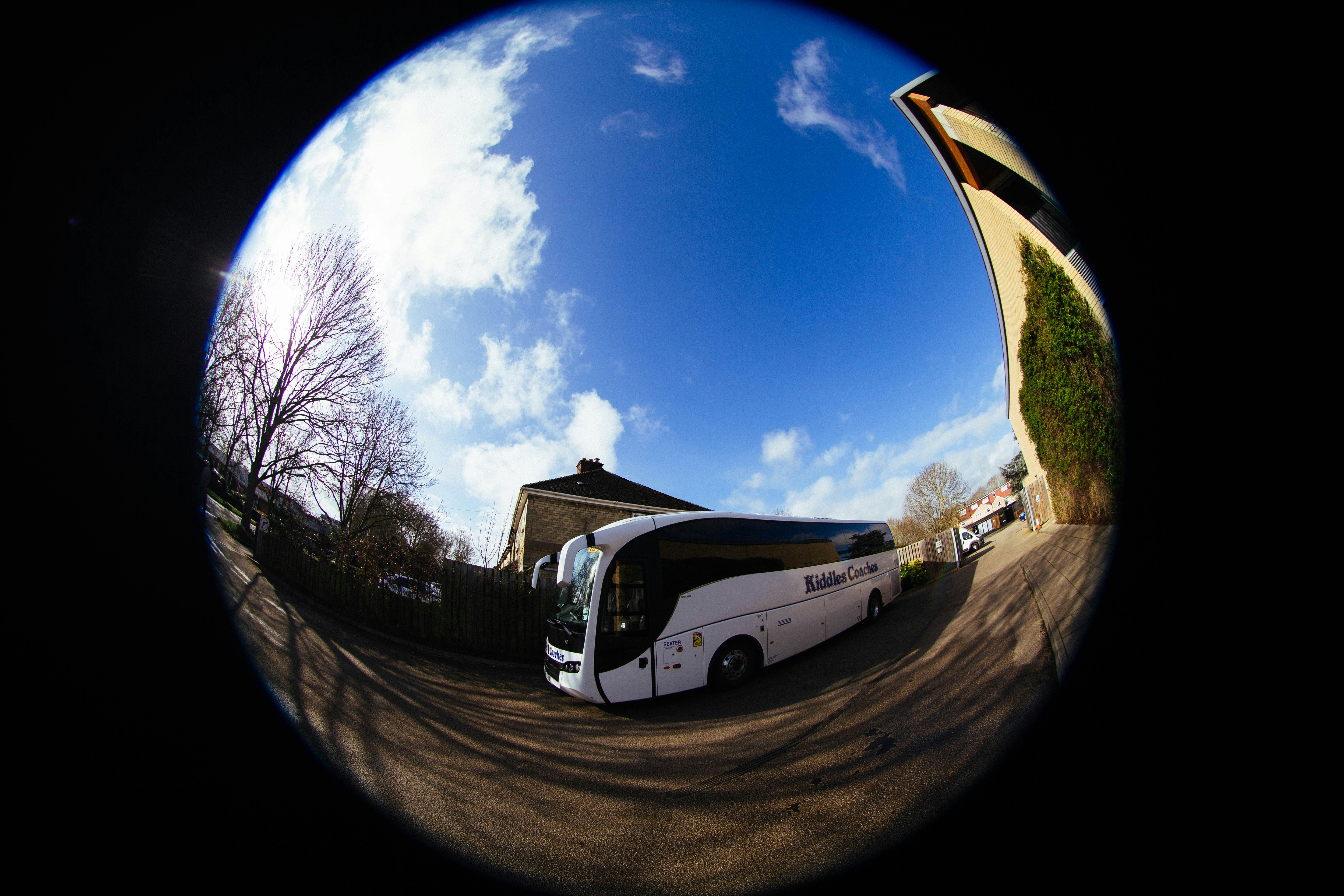 Un bus de tournée blanc garé dehors sous un ciel bleu.