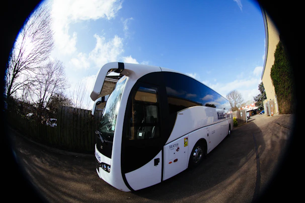 A white tour bus parked outdoors on a sunny day.