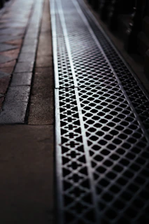 A metal grate runs along a sidewalk.