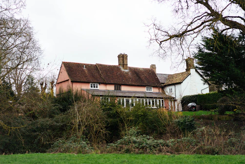 A rustic pink and white country house with trees.