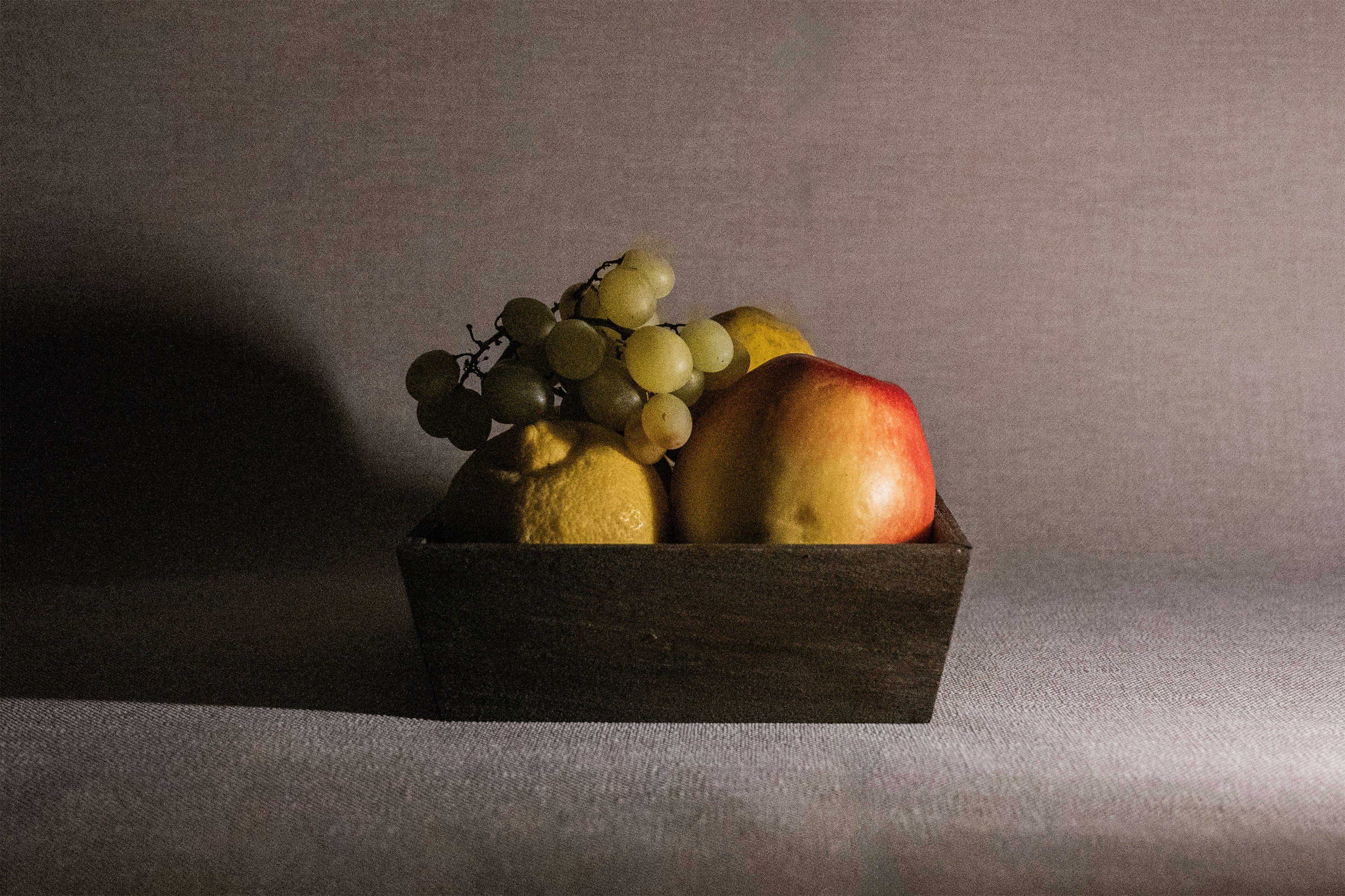 A wooden box filled with apples and grapes.
