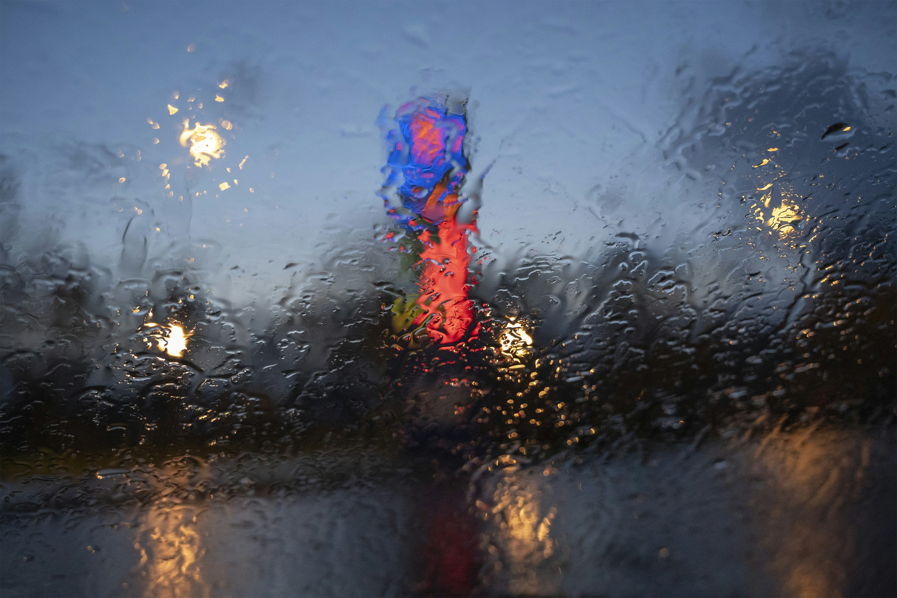 Rainy night with blurred city lights and traffic signal.