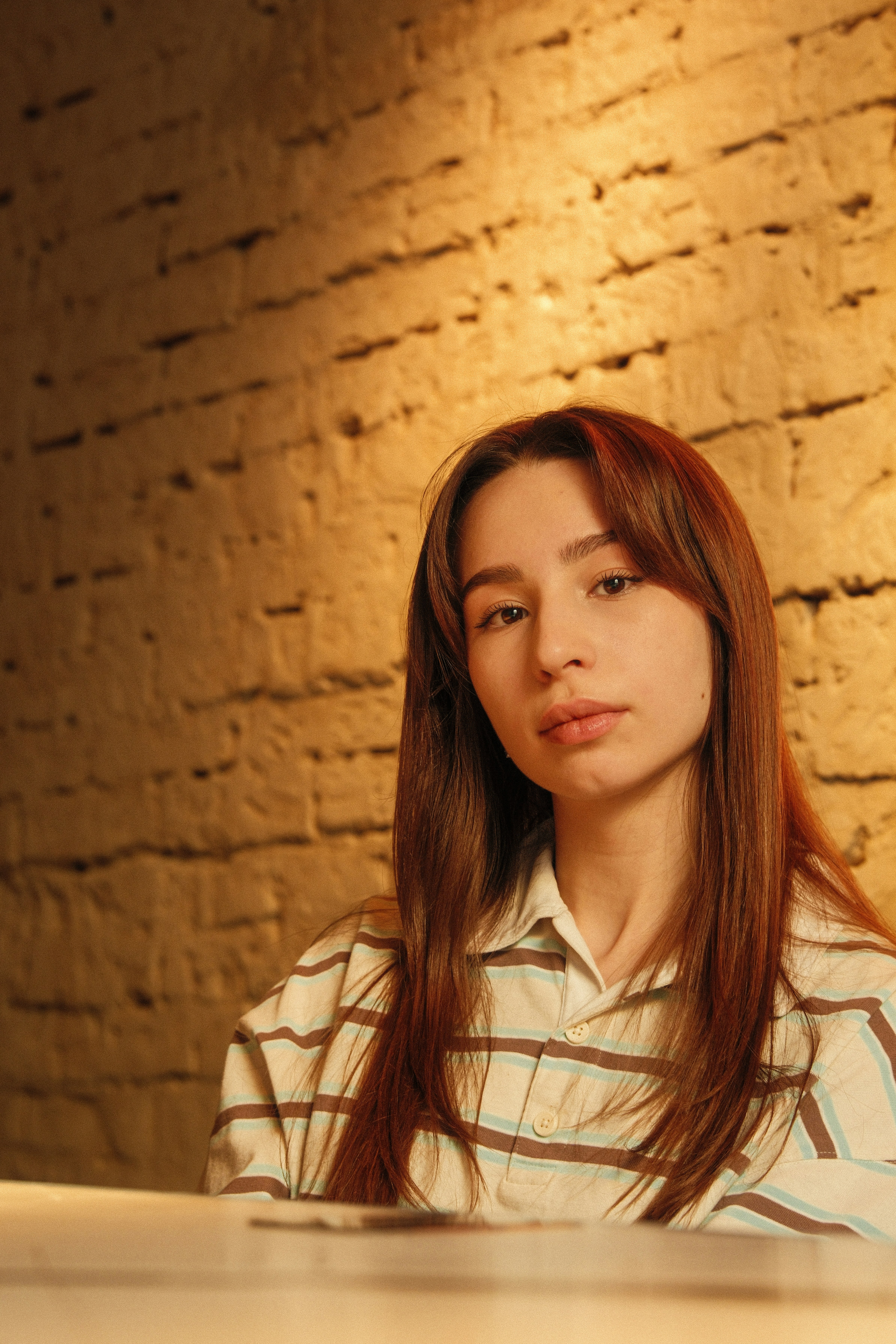Young woman with long brown hair in striped shirt.