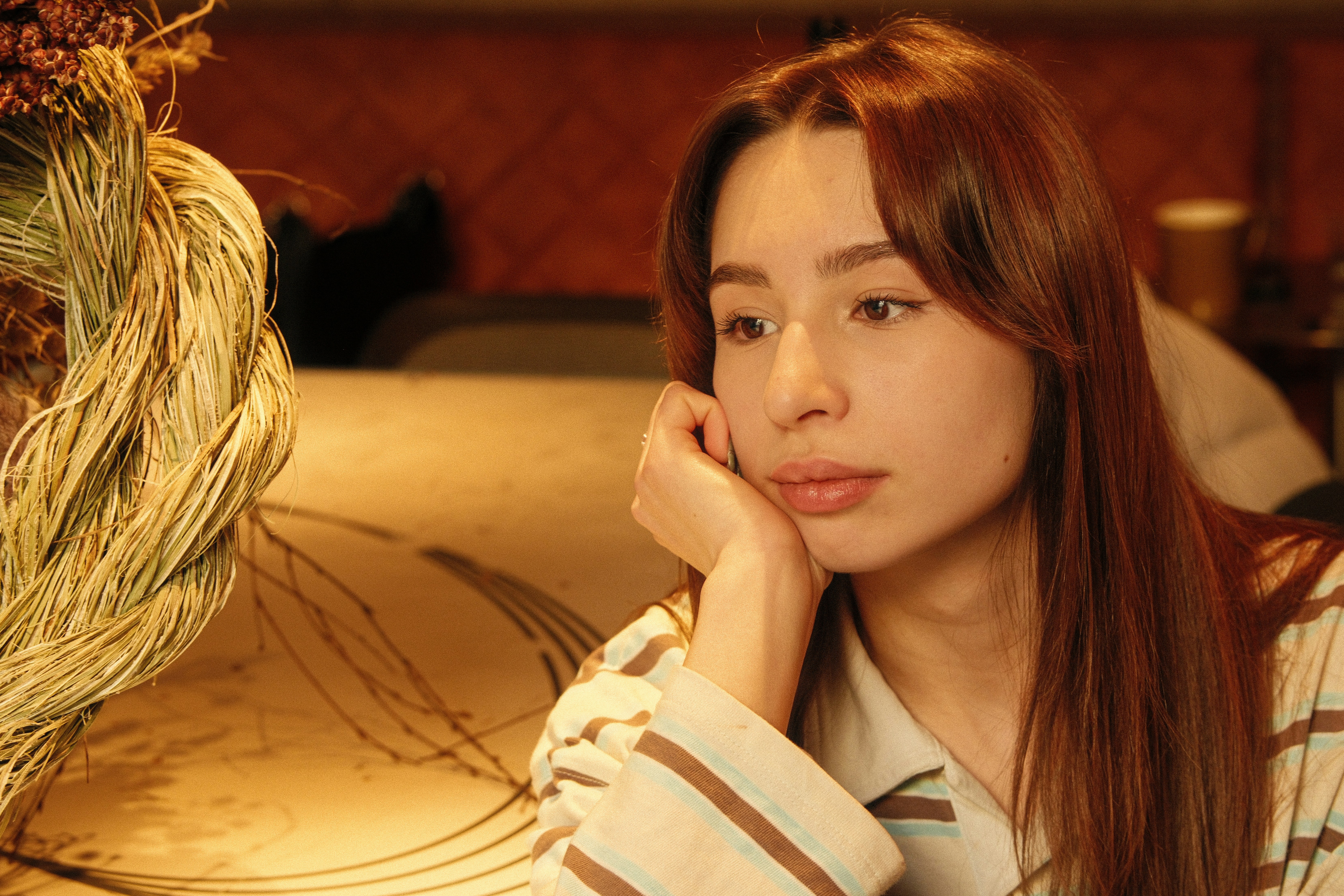 Young woman with long auburn hair resting chin