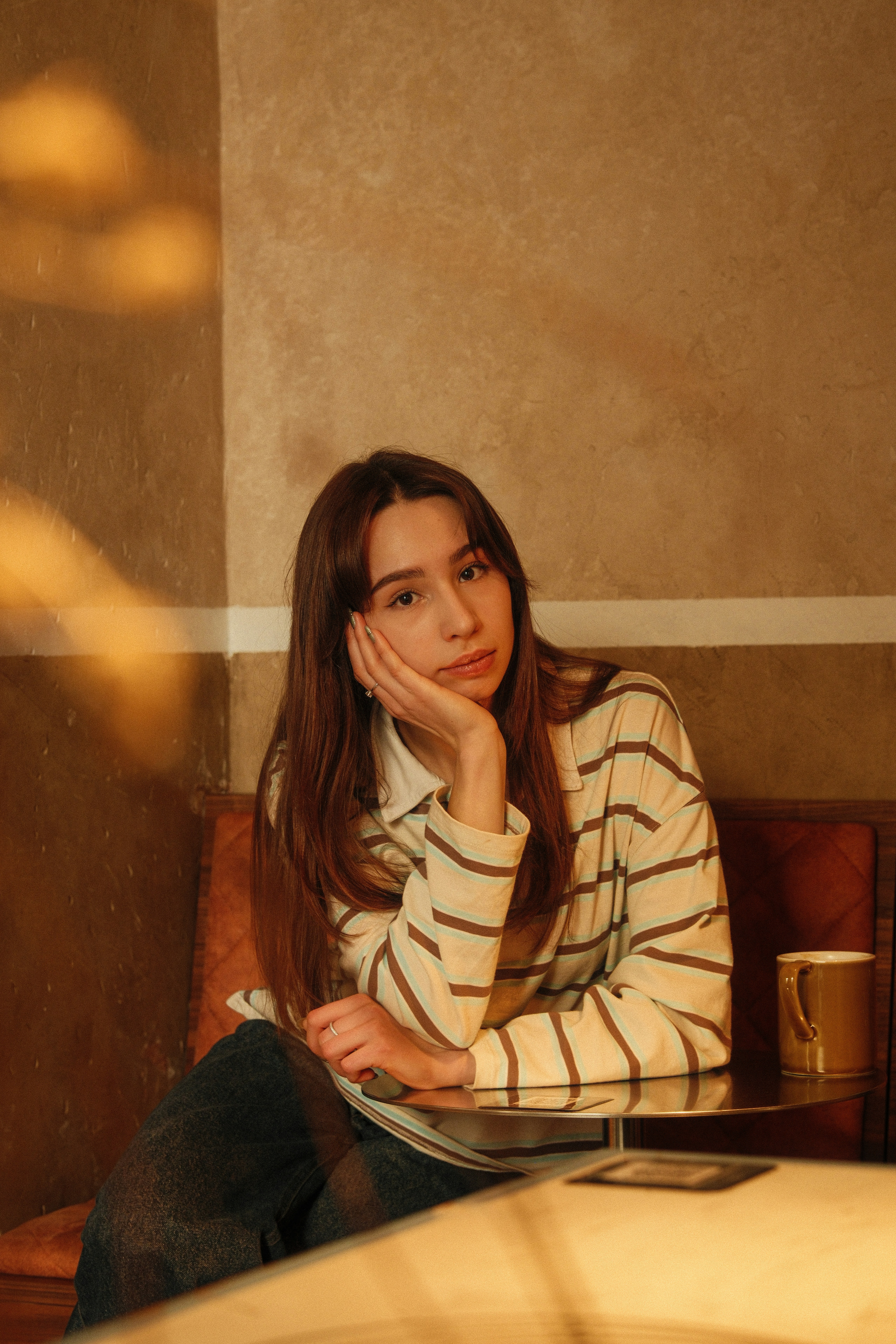 A young woman sits with her hand on her chin.