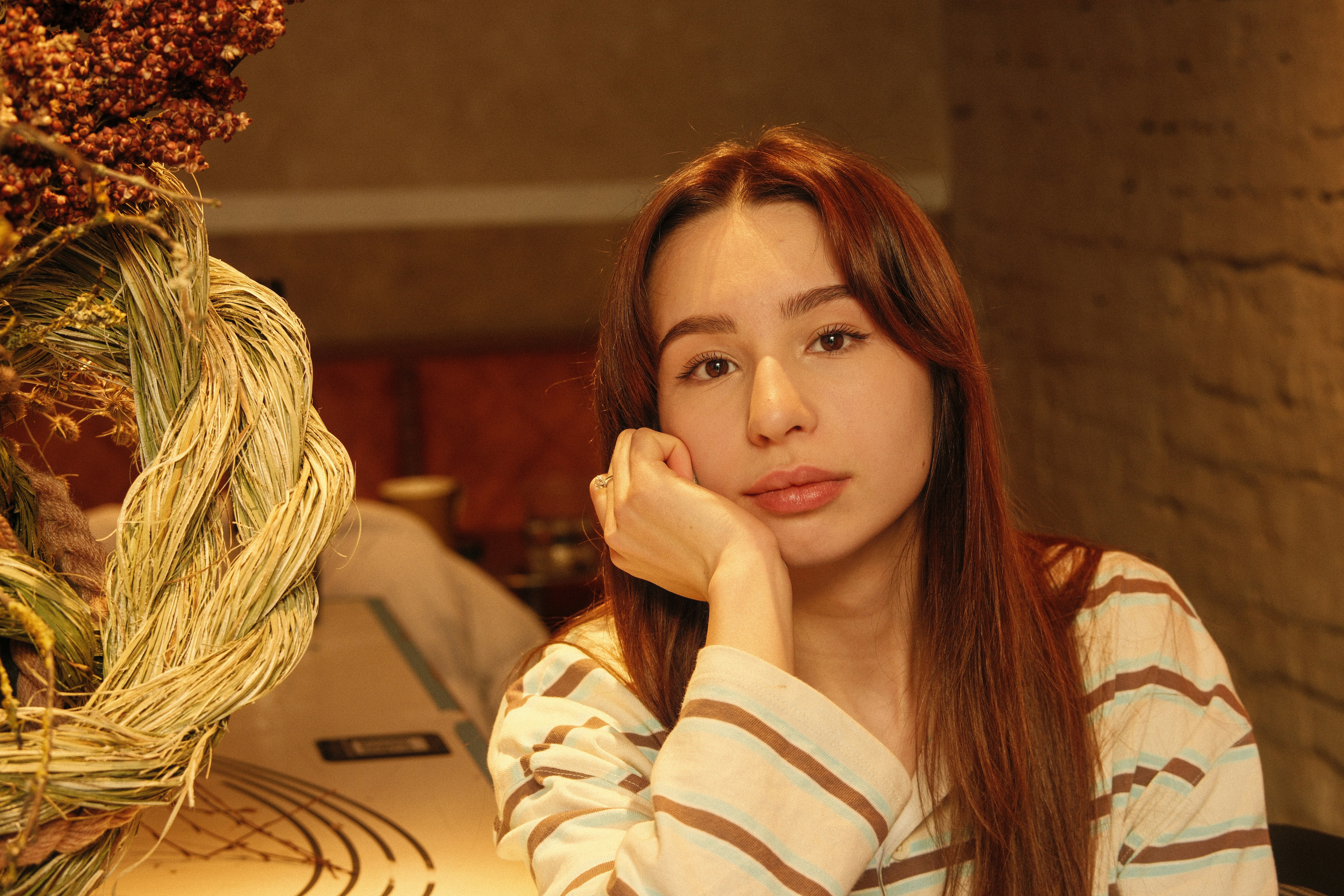 Young woman with long brown hair resting chin on hand