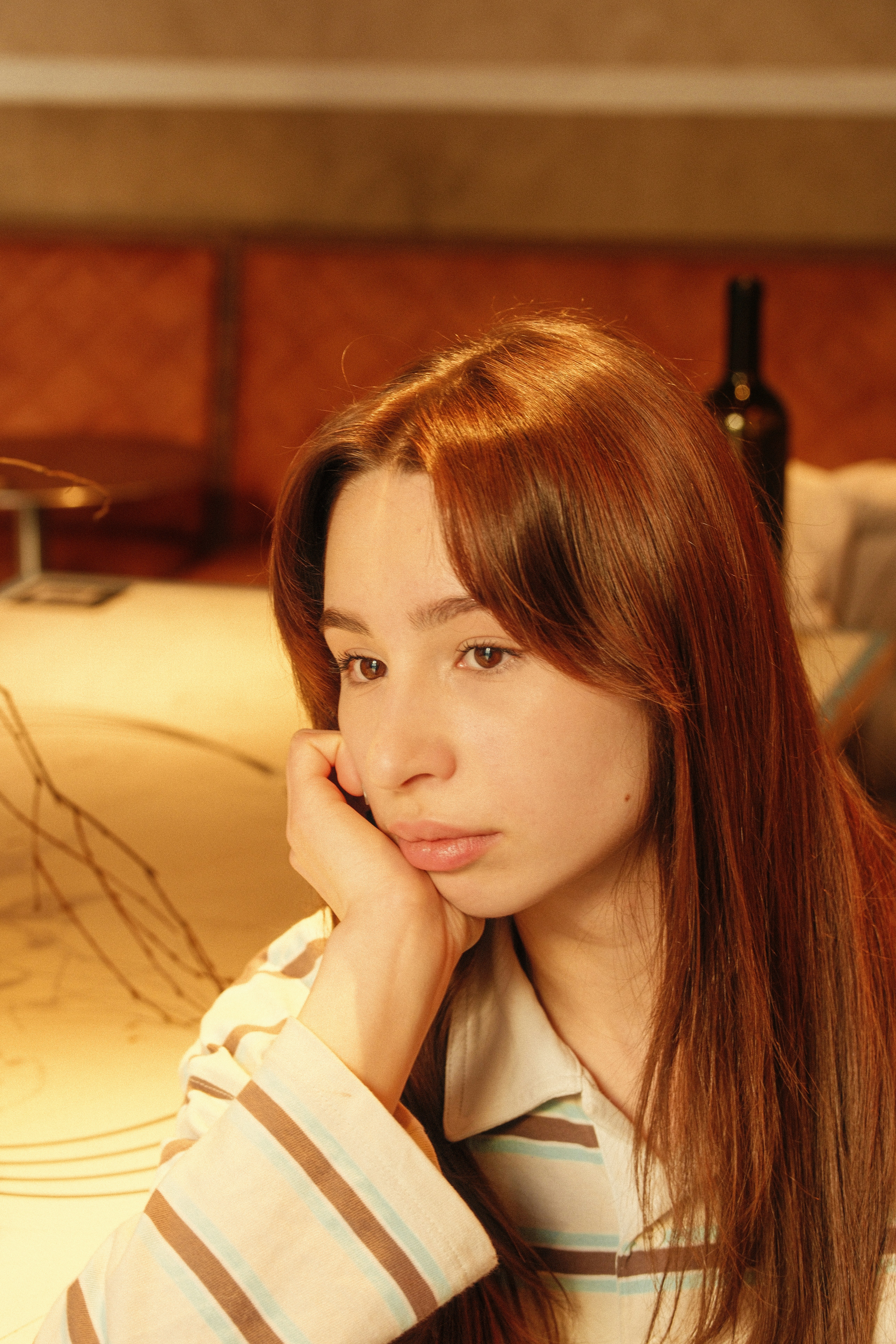 A young woman rests her chin on her hand.