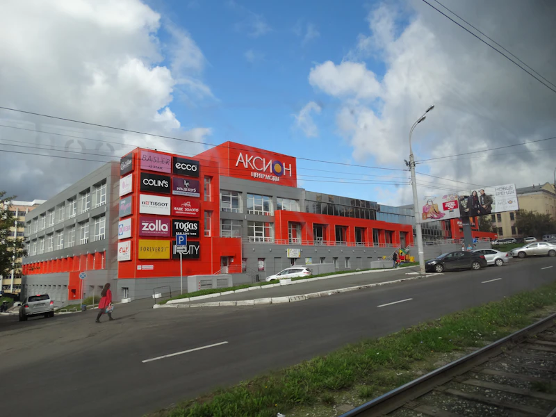 Modern shopping mall exterior with large retail facades and promotional signage