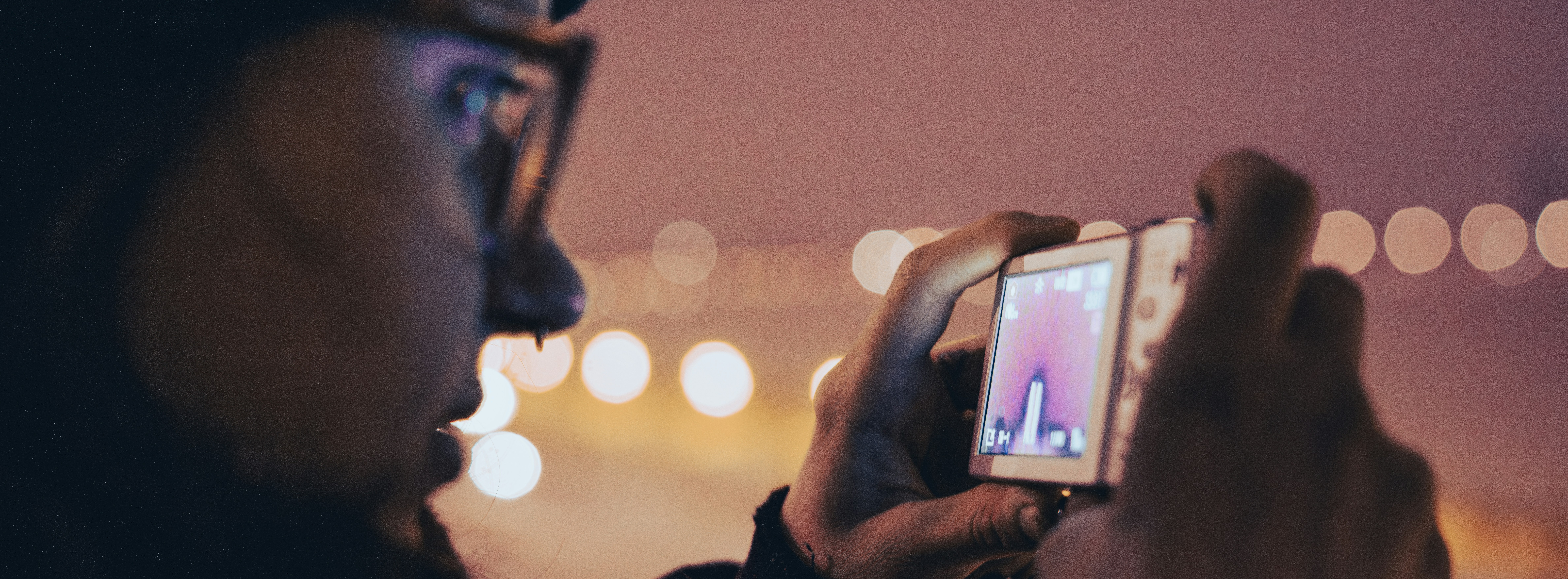 Person filming with a small digital camera at night