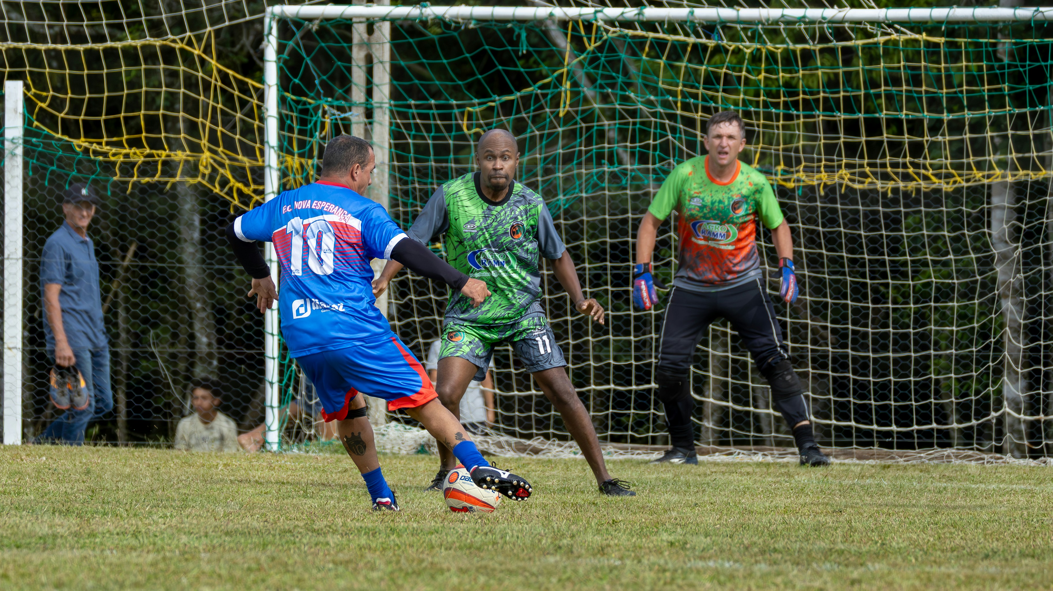 Soccer players competing on a grassy field near goal.