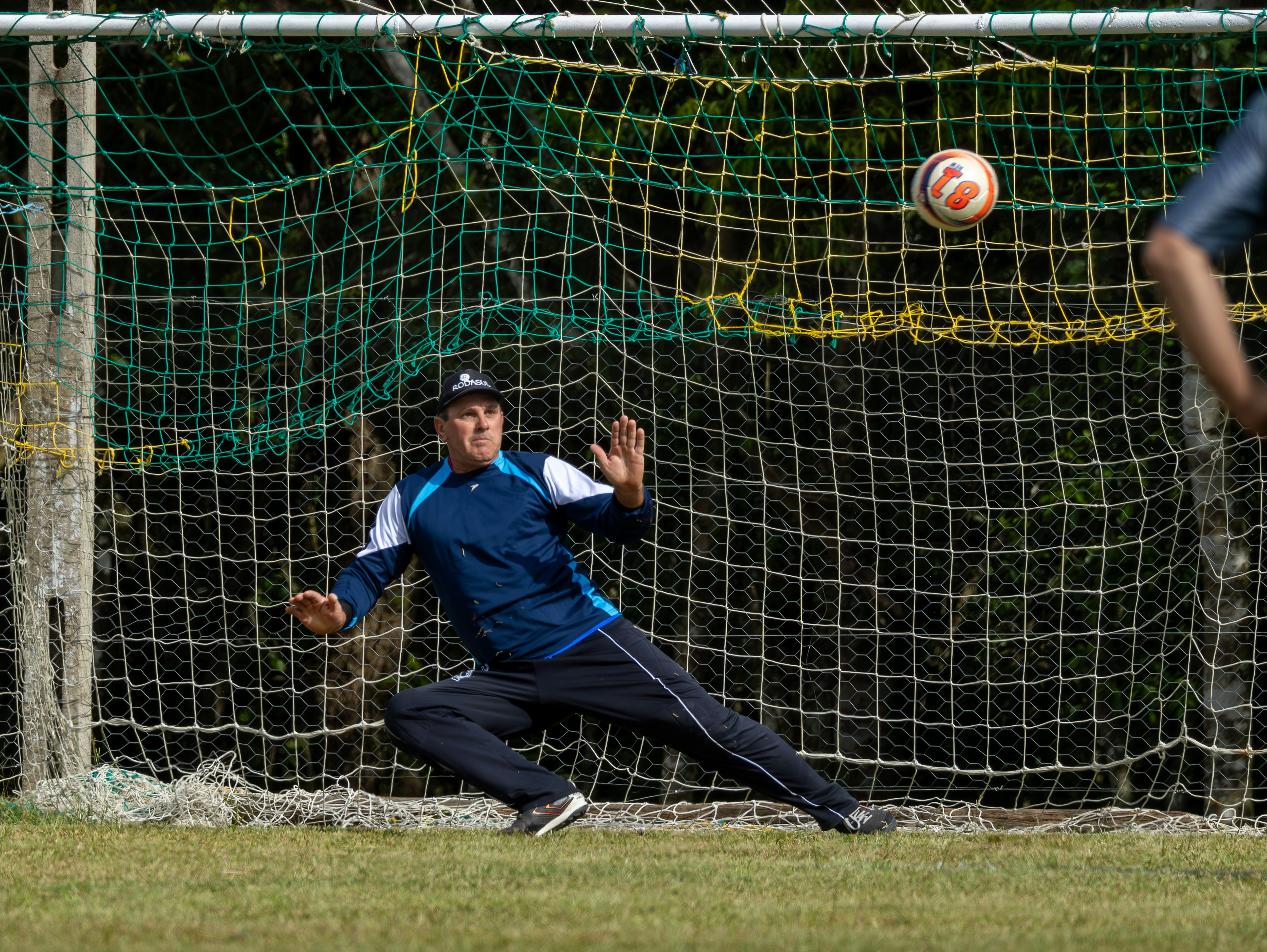 Goalkeeper dives for the ball near the net.