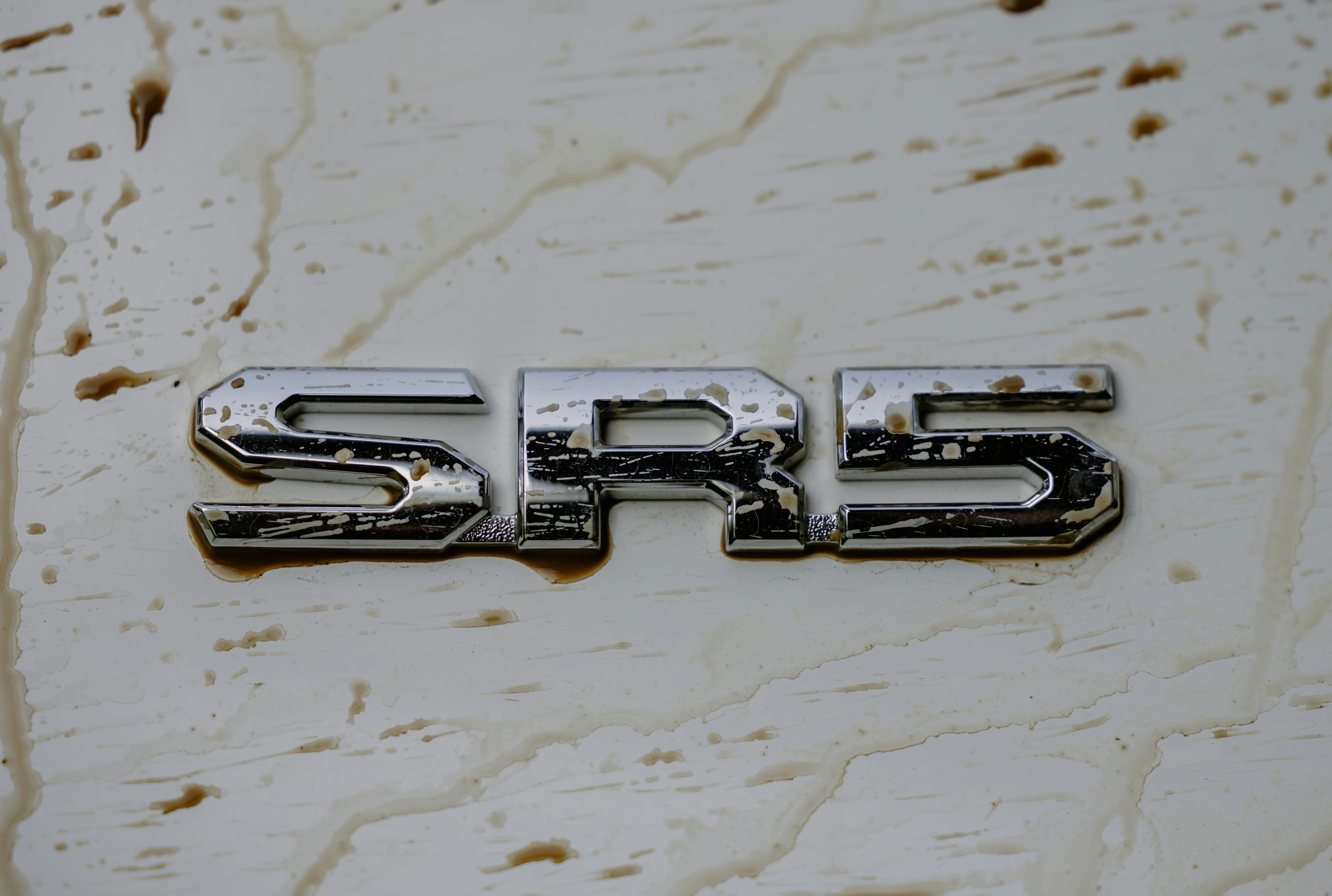 Emblema prateado SRS em superfície branca suja