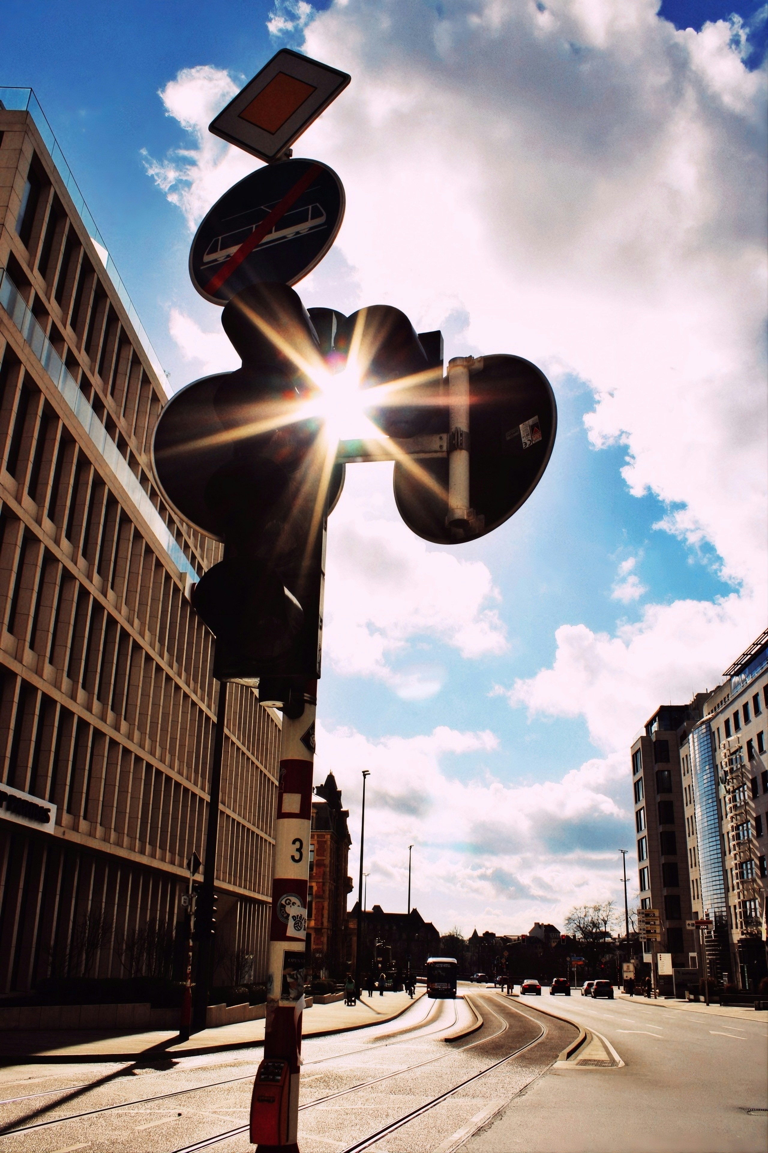 Sun flares through traffic signal on city street