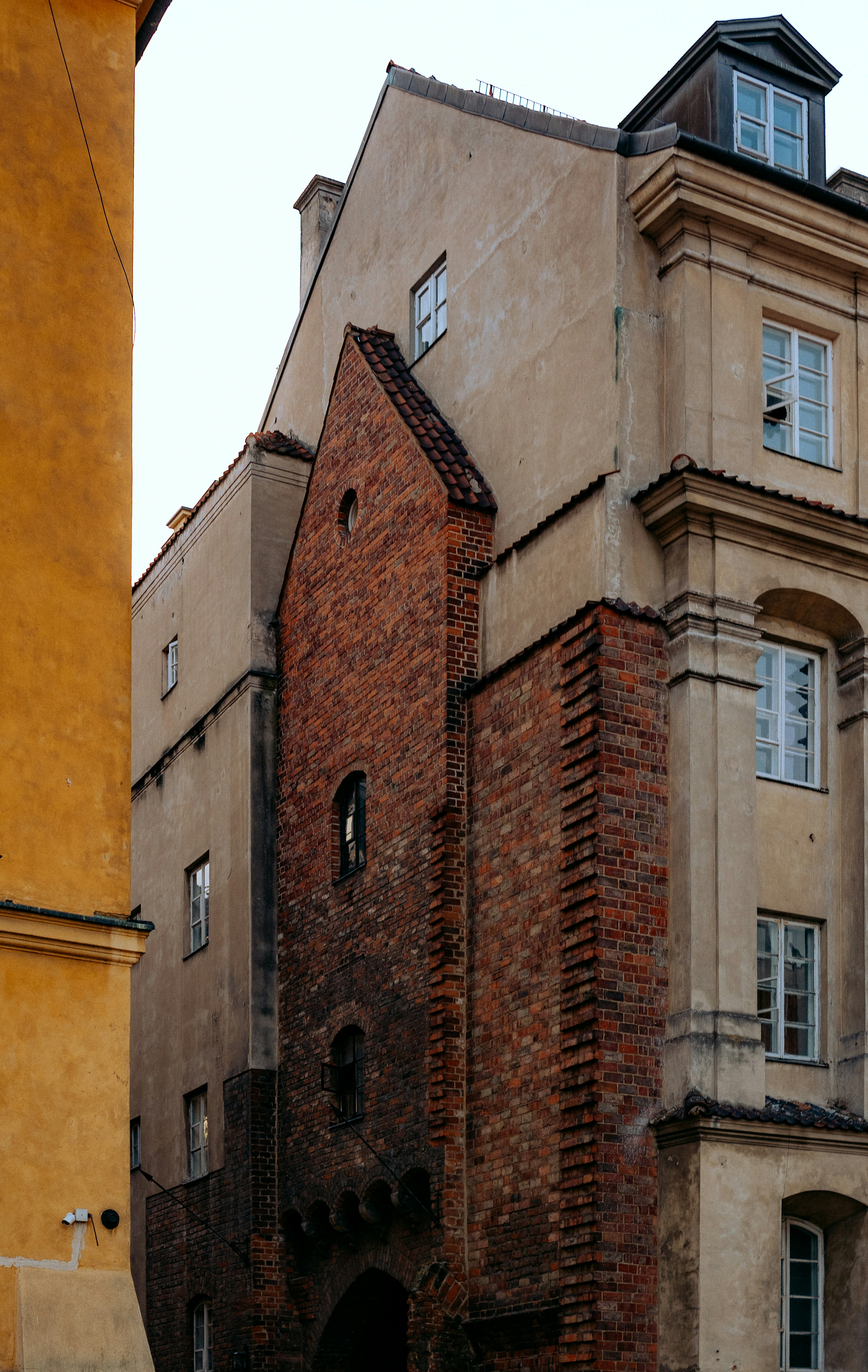 Old brick building with beige facade and windows.