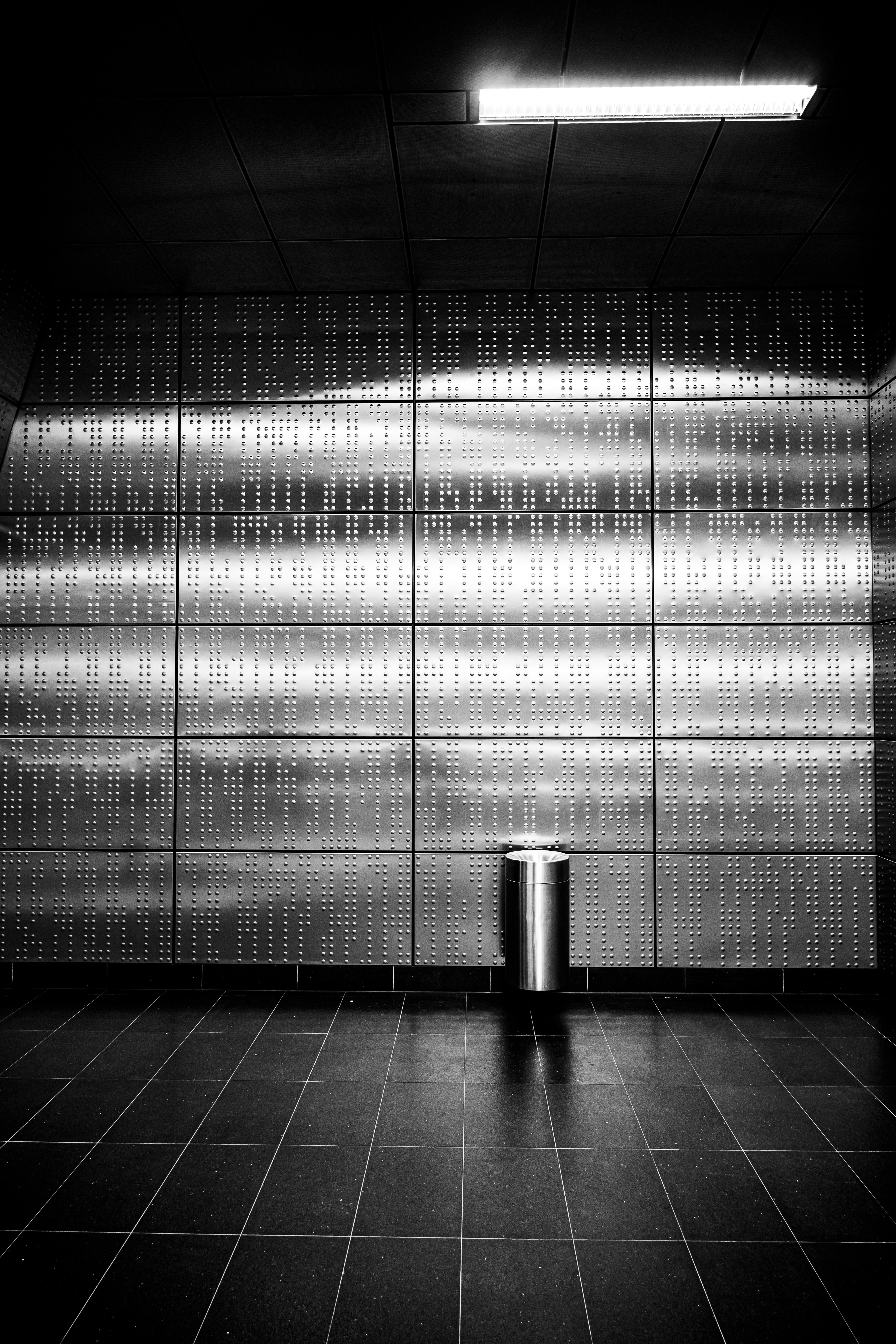 Mur métallique moderne avec poubelle et sol carrelé.