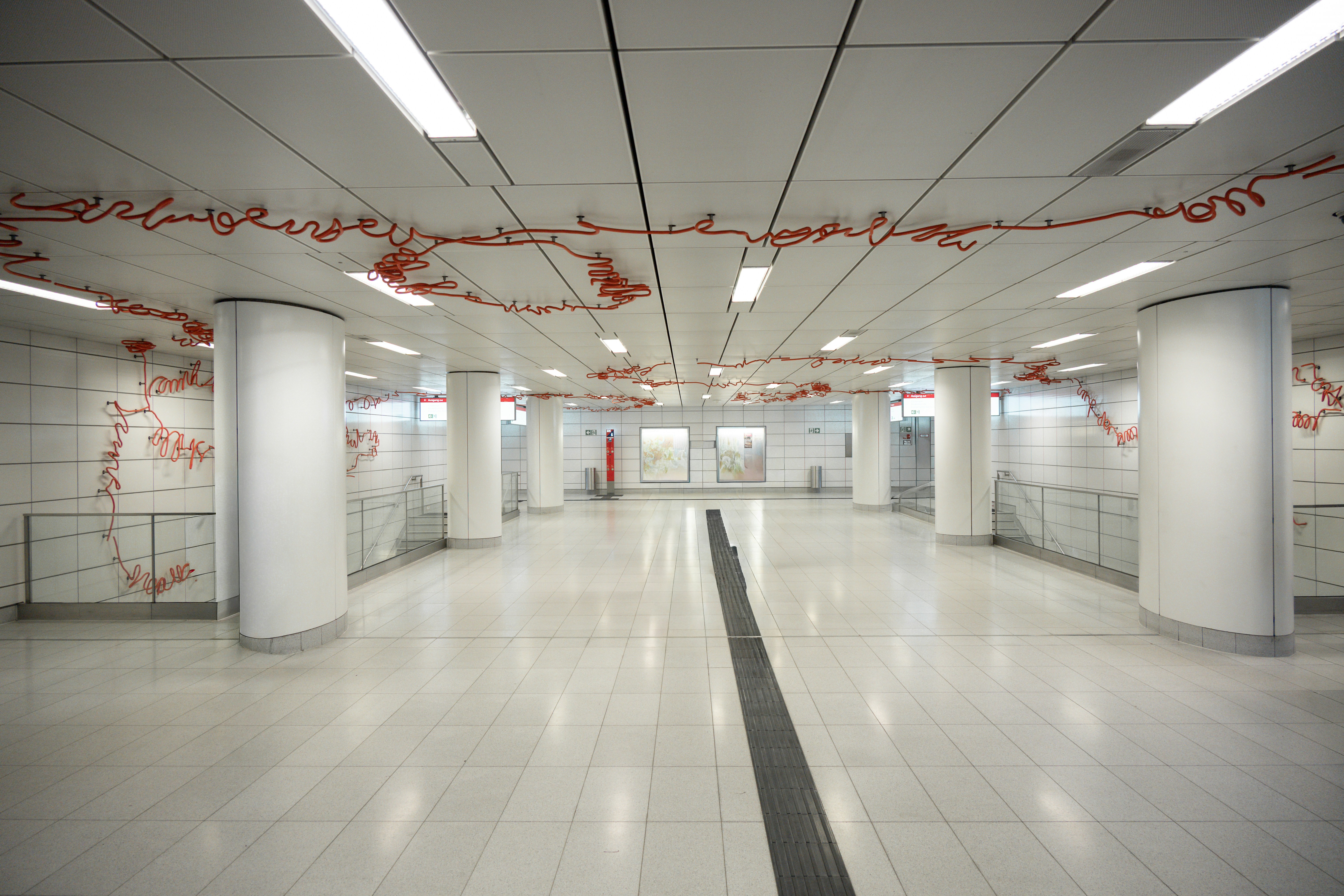 Intérieur moderne d’une station de métro avec colonnes blanches et peinture rouge.