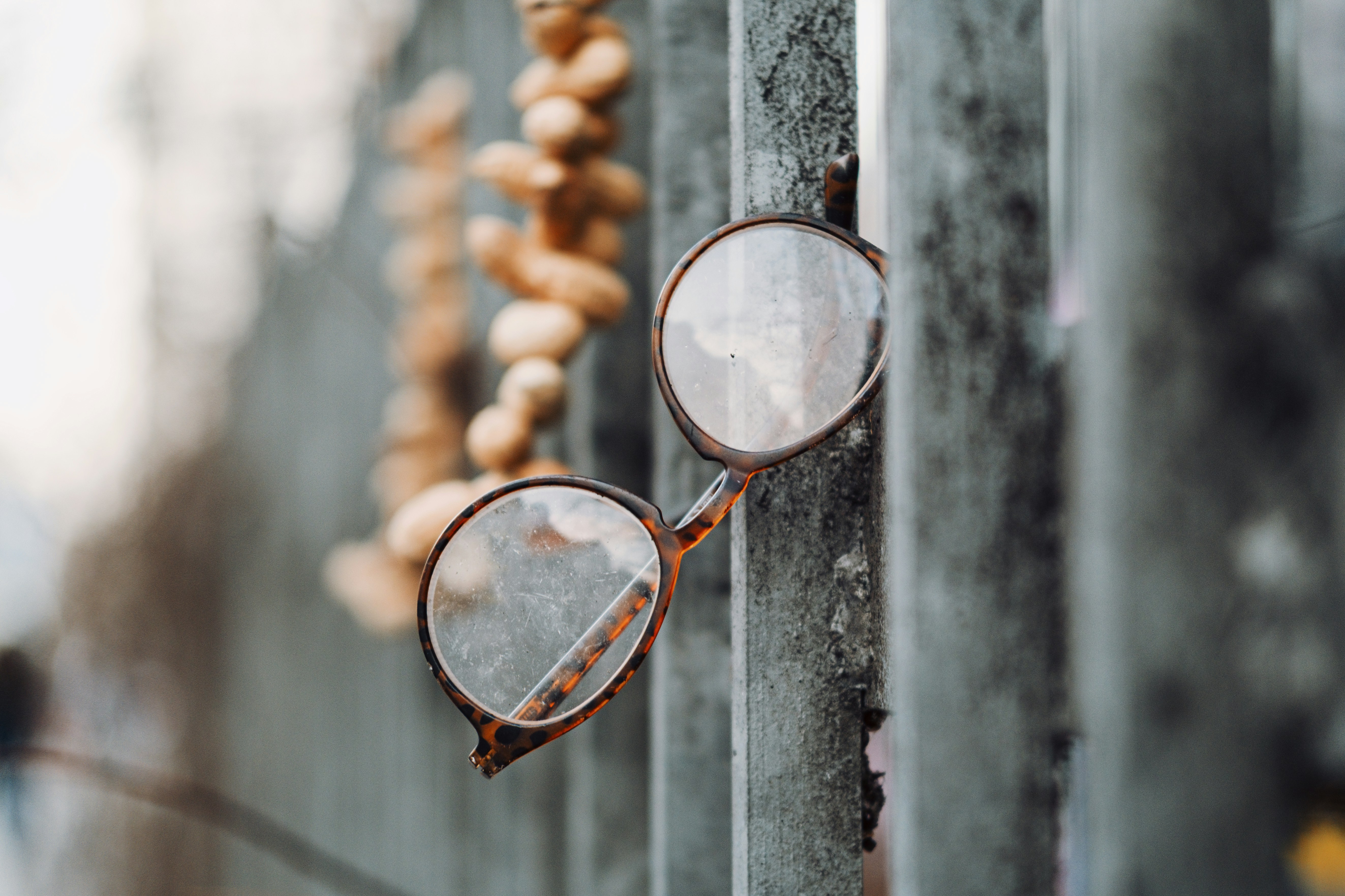 Des lunettes rondes suspendues à une clôture usée.