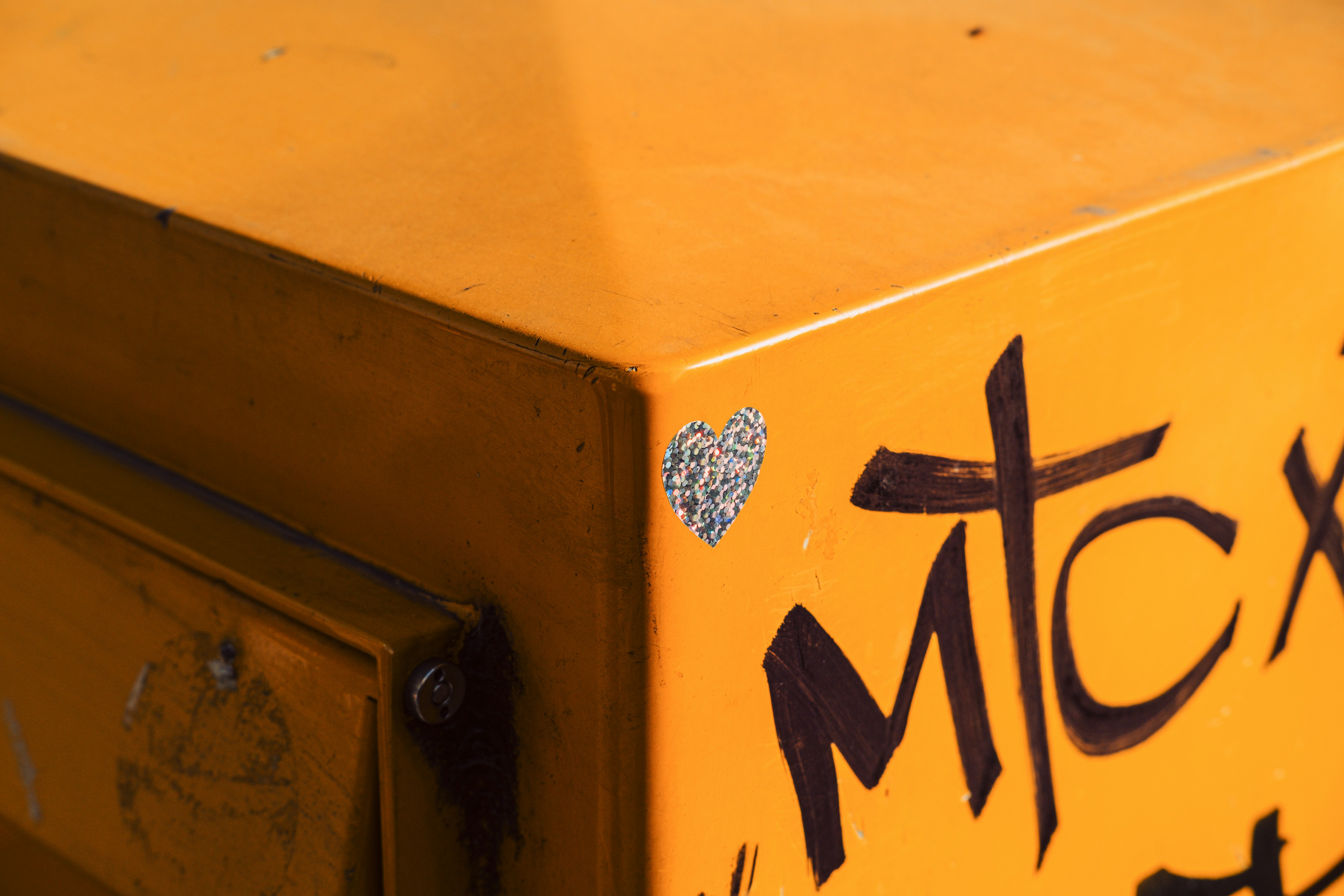 Boîte métallique orange avec des graffitis et un cœur