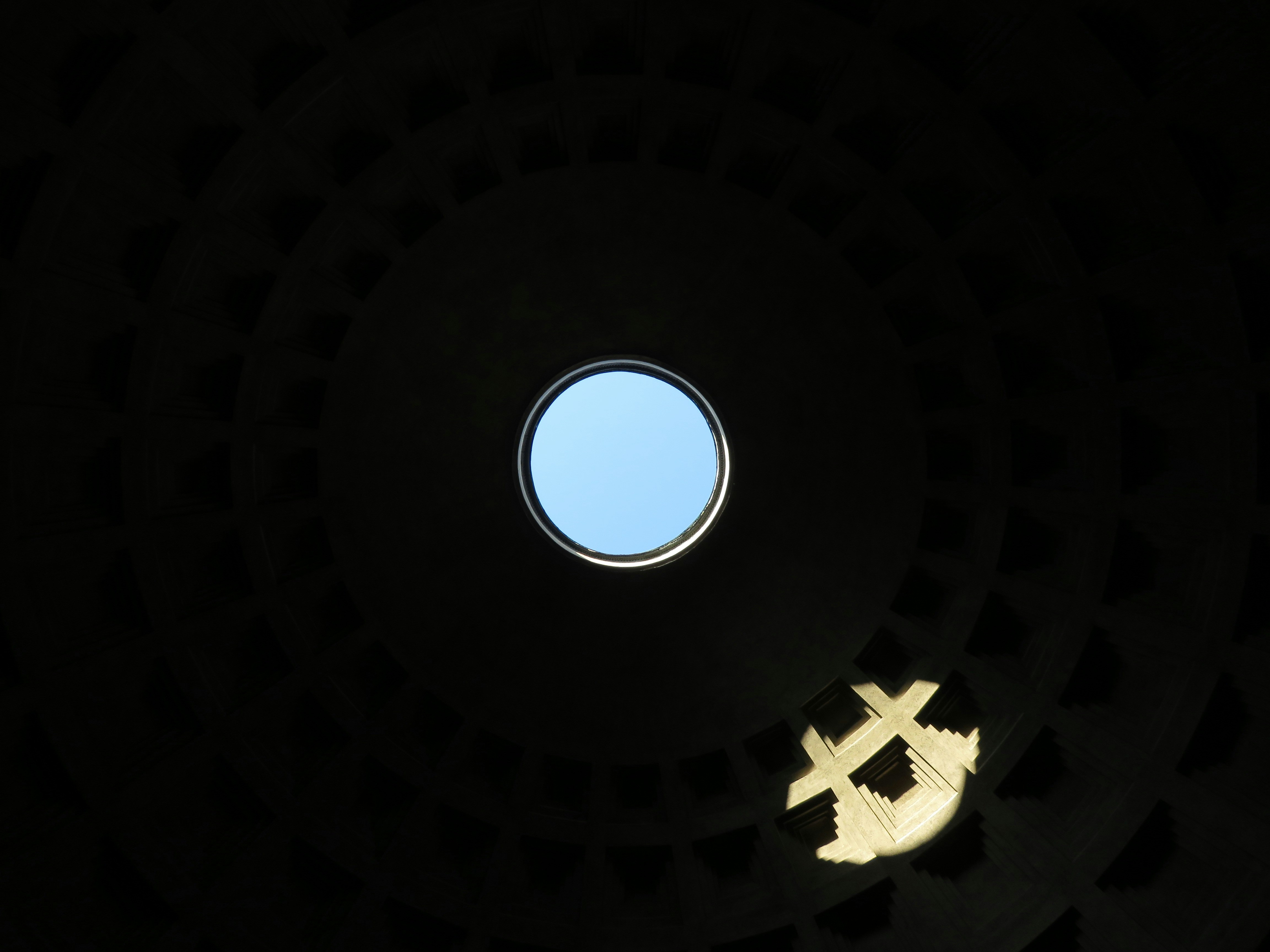Ouverture circulaire dans le plafond sombre montrant un ciel bleu