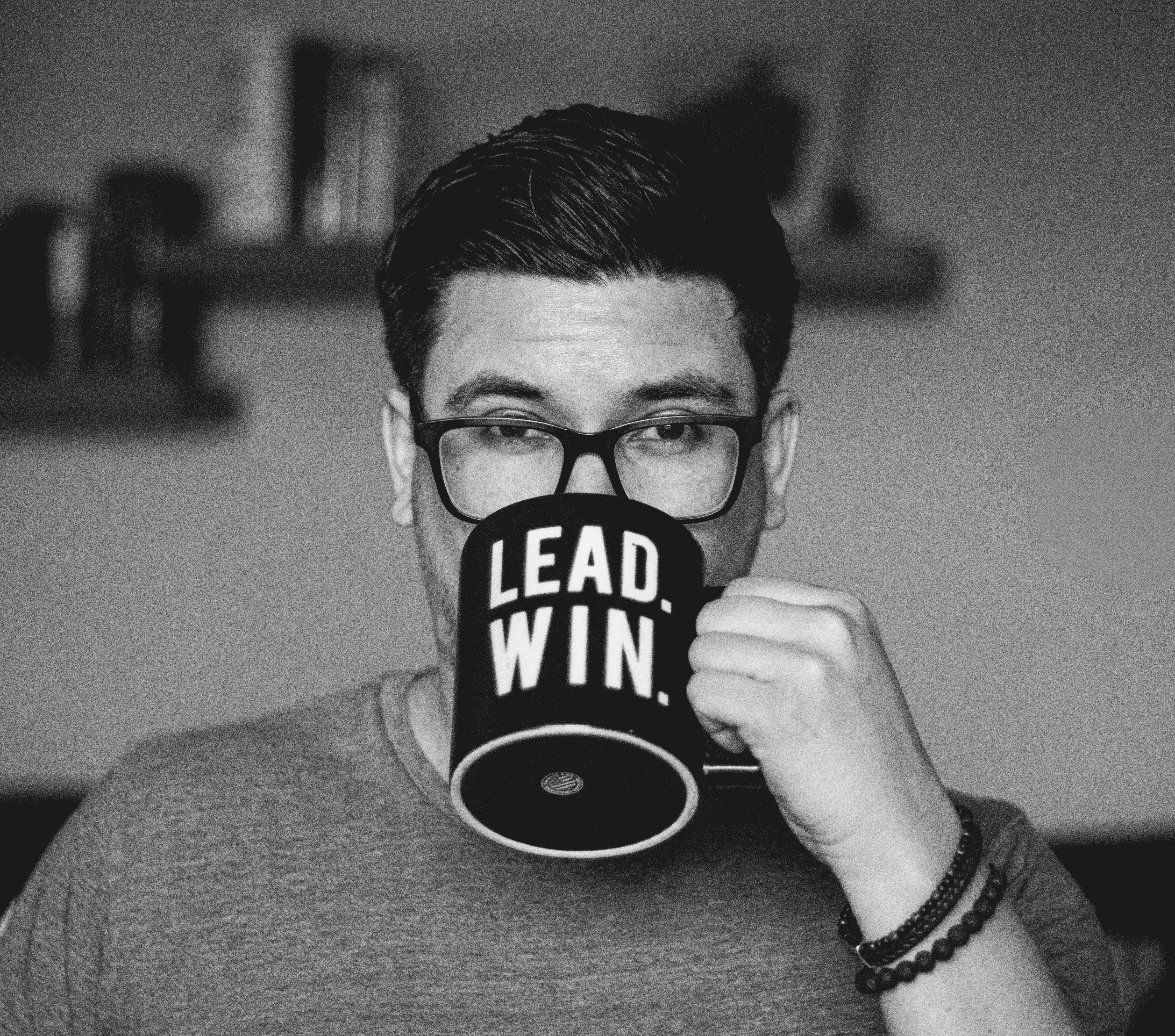 Man wearing glasses drinks from a mug