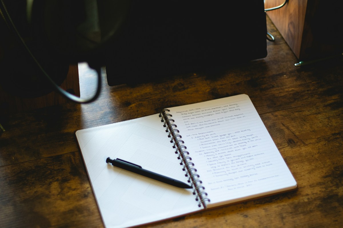 Open notebook with a pen on a wooden desk, ideal for jotting down getting-to-know-you questions for team building activities.