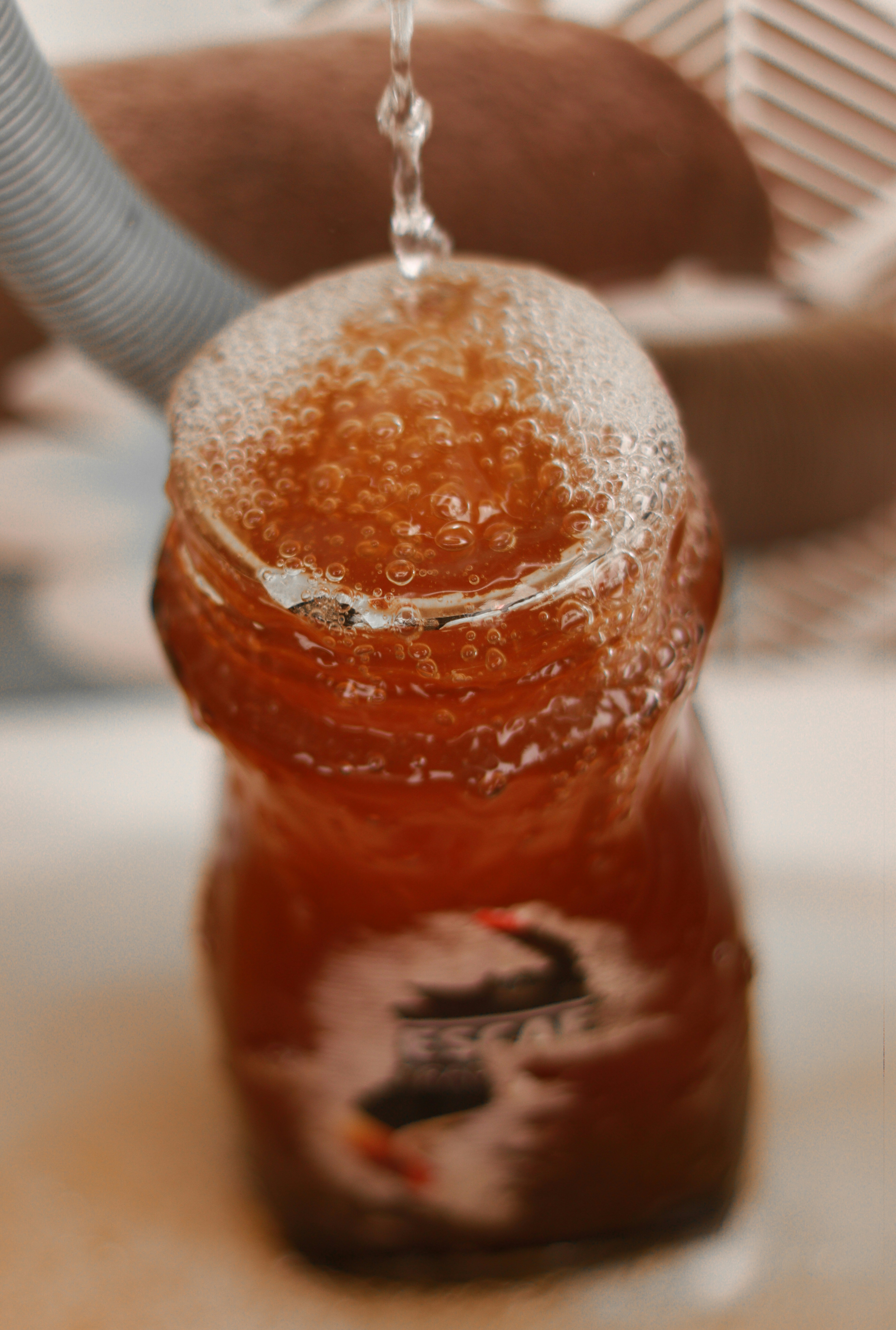 Water pouring into a bubbly brown liquid in a bottle.