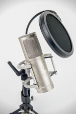 A studio microphone on a stand with pop filter