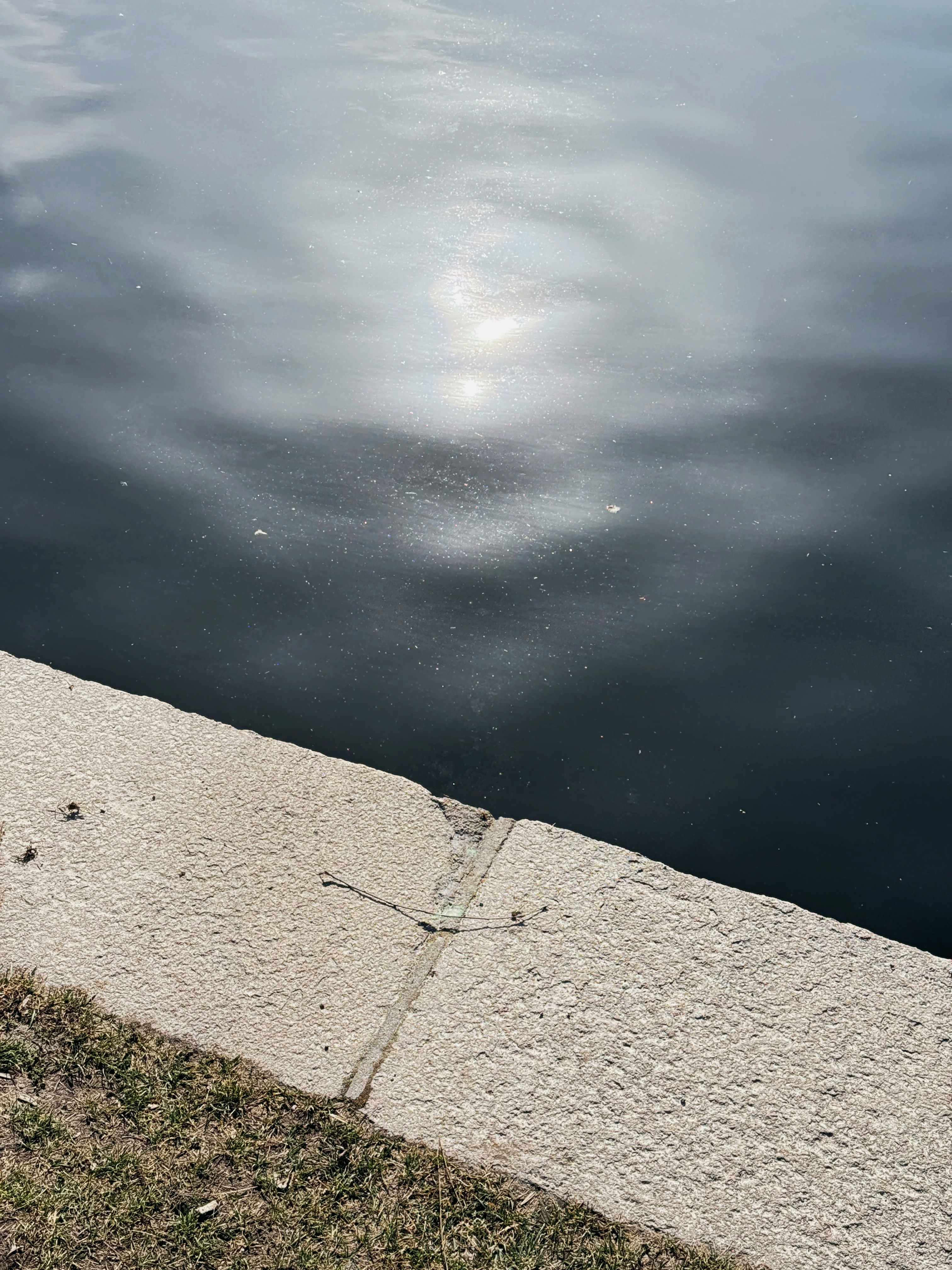 La luce del sole si riflette su un corpo d'acqua scuro e ondulato.
