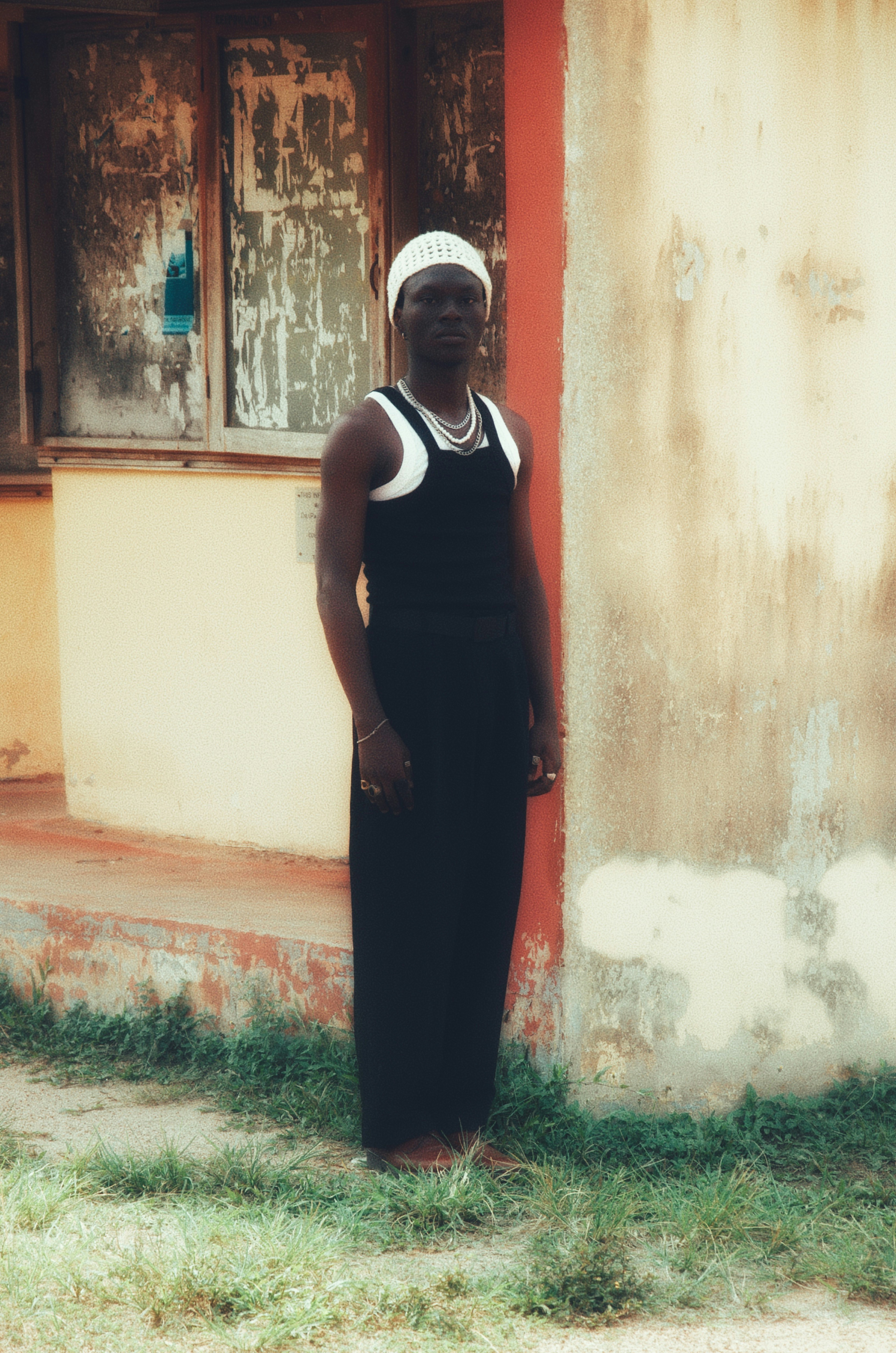 Uomo in abito nero e berretto bianco sta fuori.