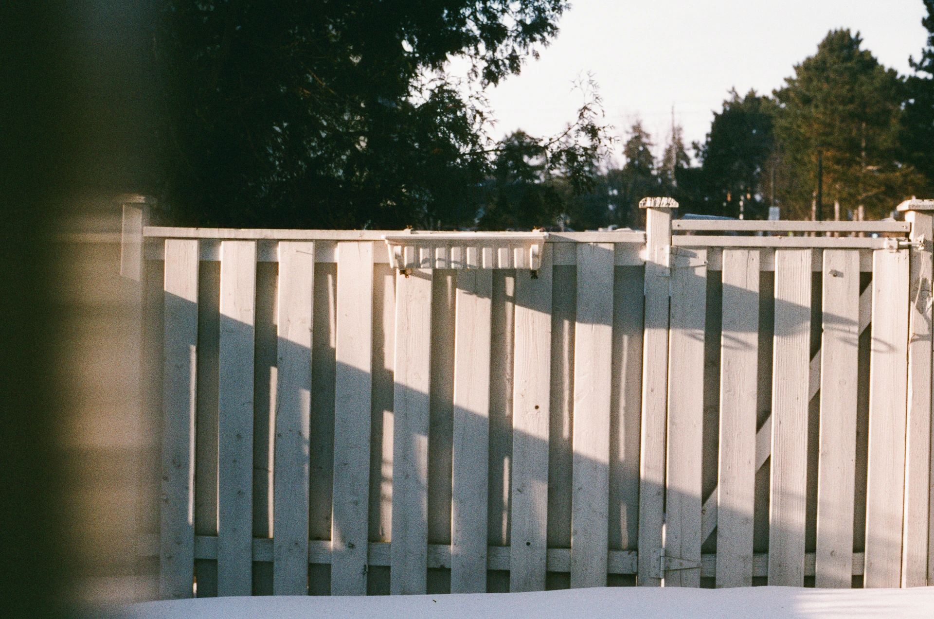 White picket fence with shadows on snow