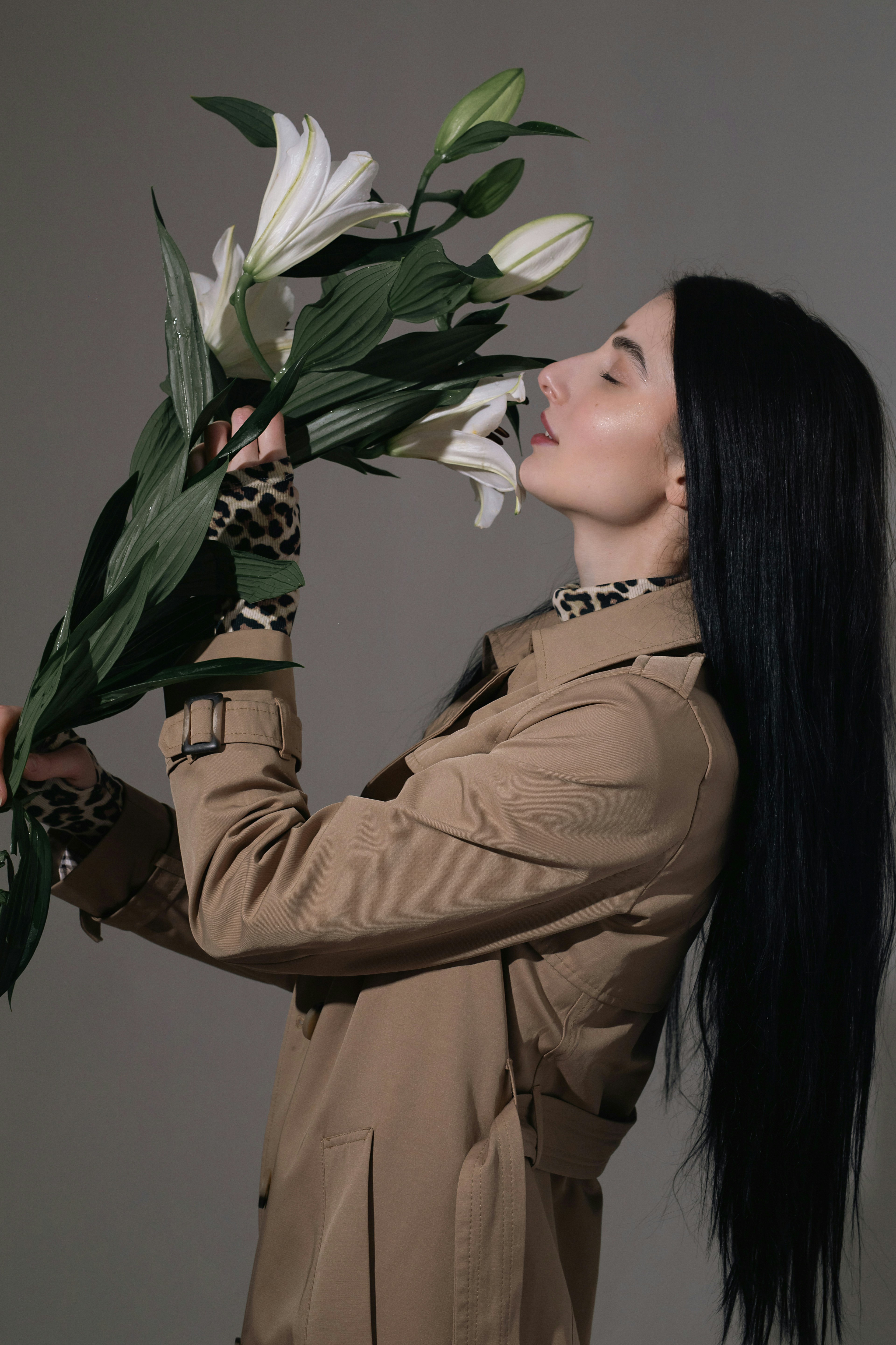 目を閉じて白いユリの香りを嗅ぐ女性