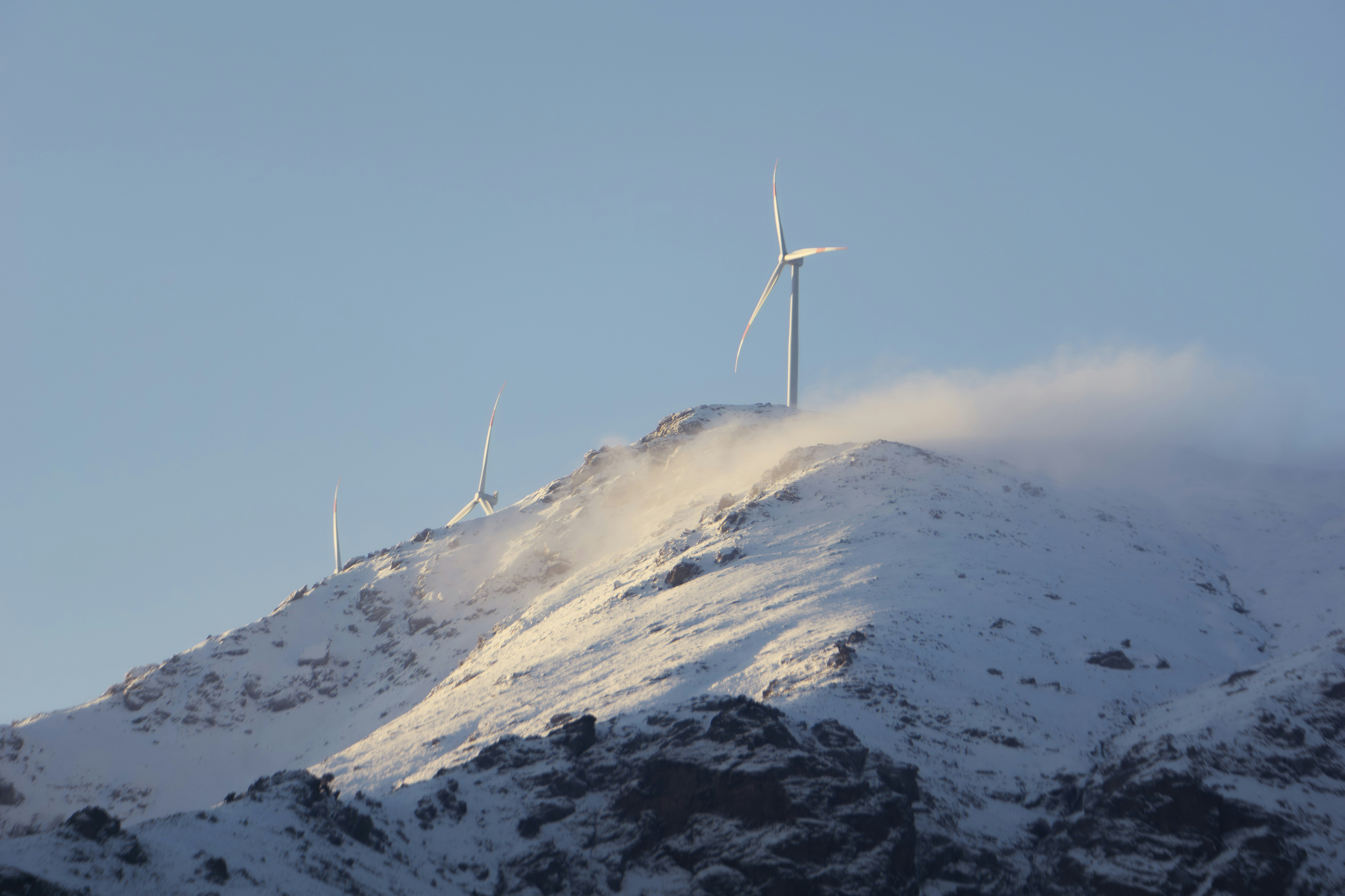 Wind turbines on a snowy mountain peak