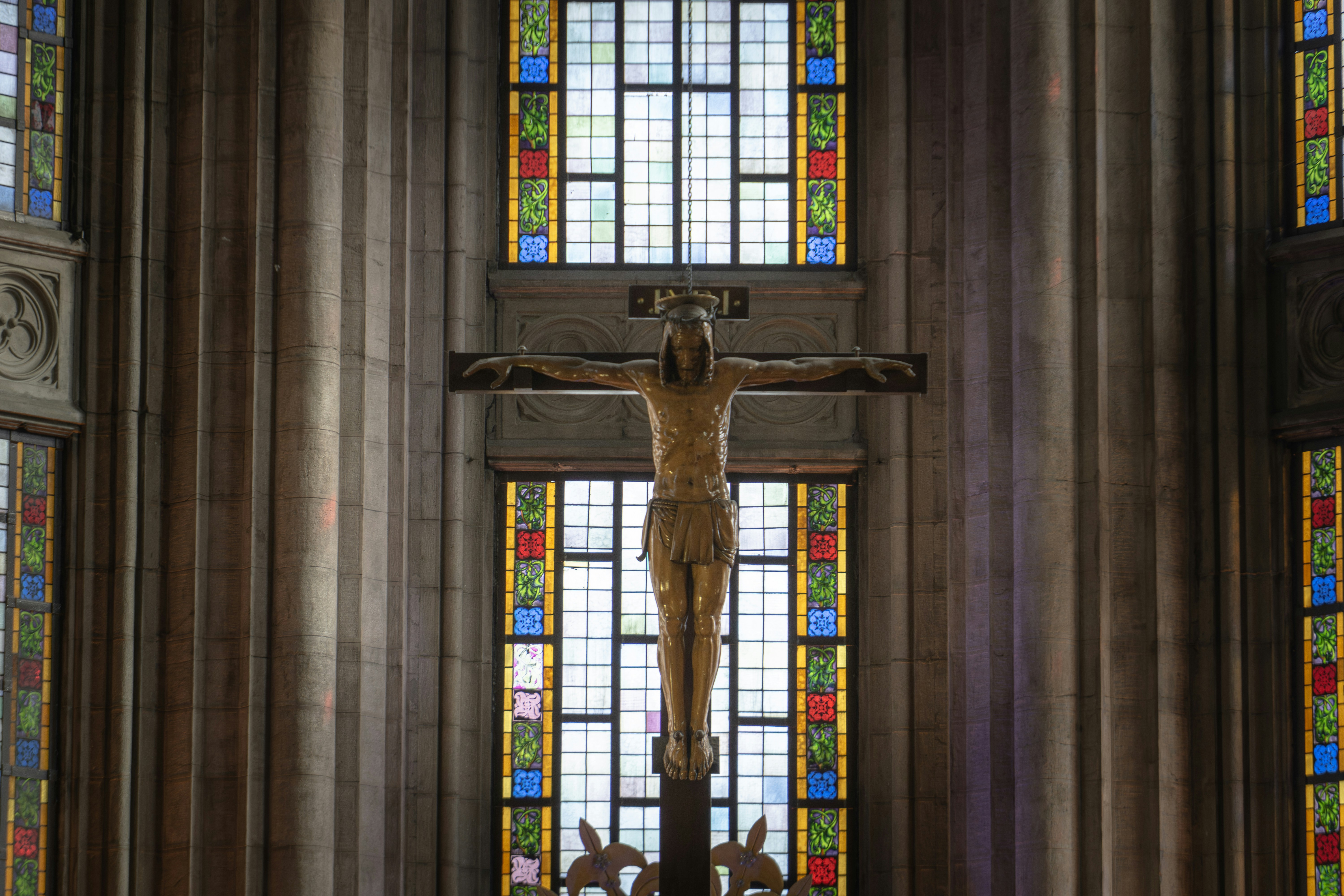 Wooden crucifix with stained glass windows behind