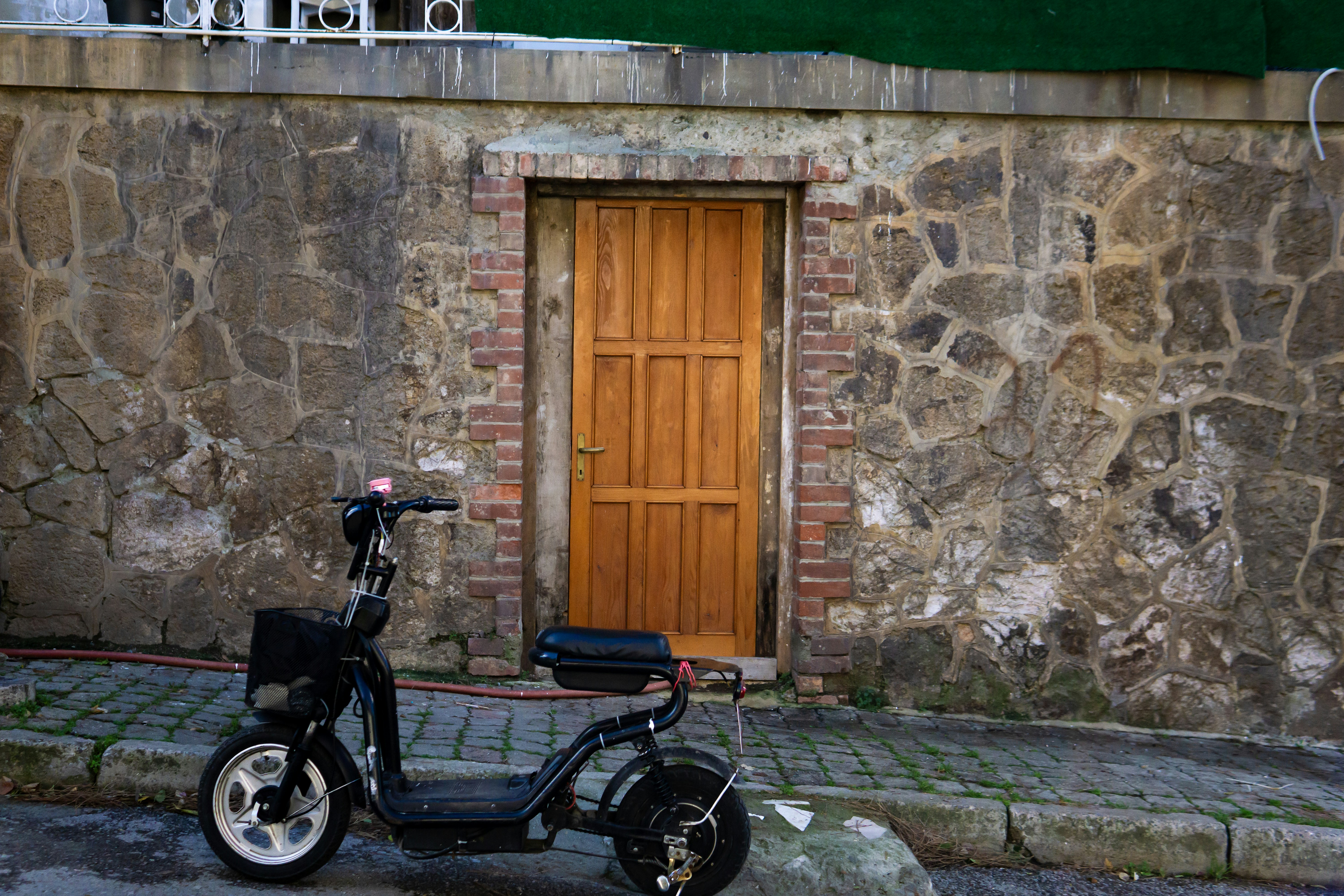 A black scooter parked in front of a wooden door.