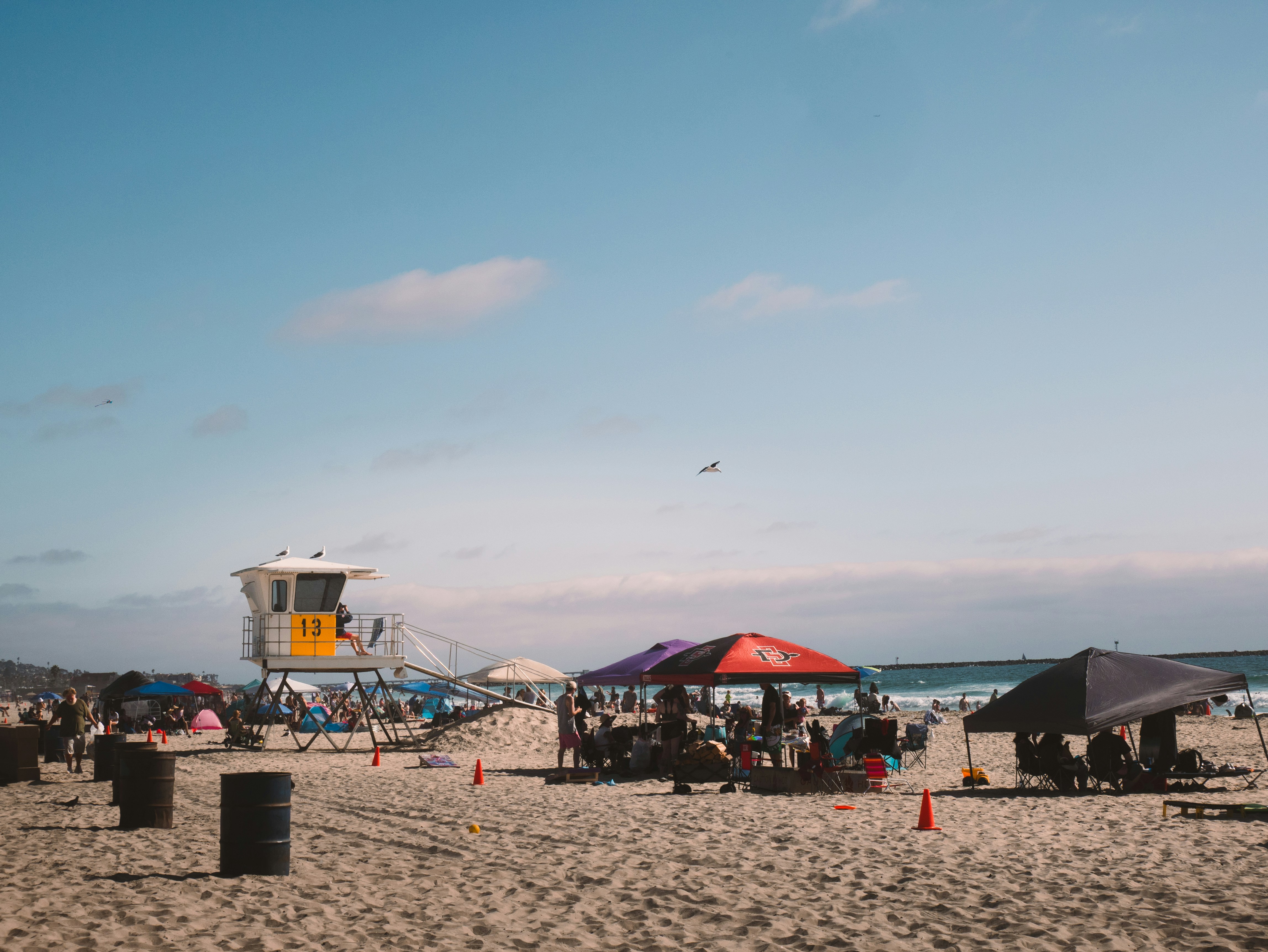 People relax under umbrellas on a sandy beach.