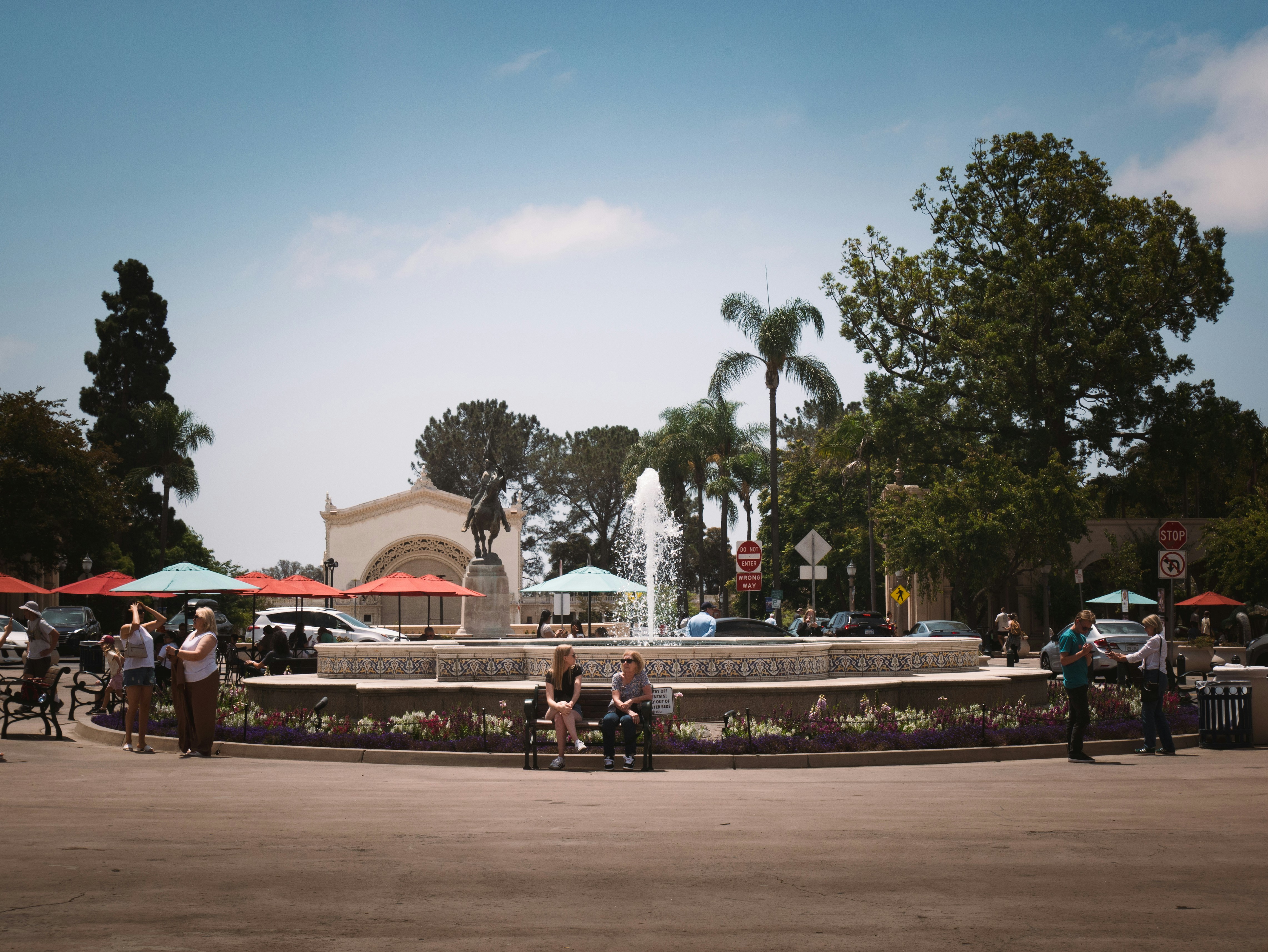 People gather around a fountain in a park.