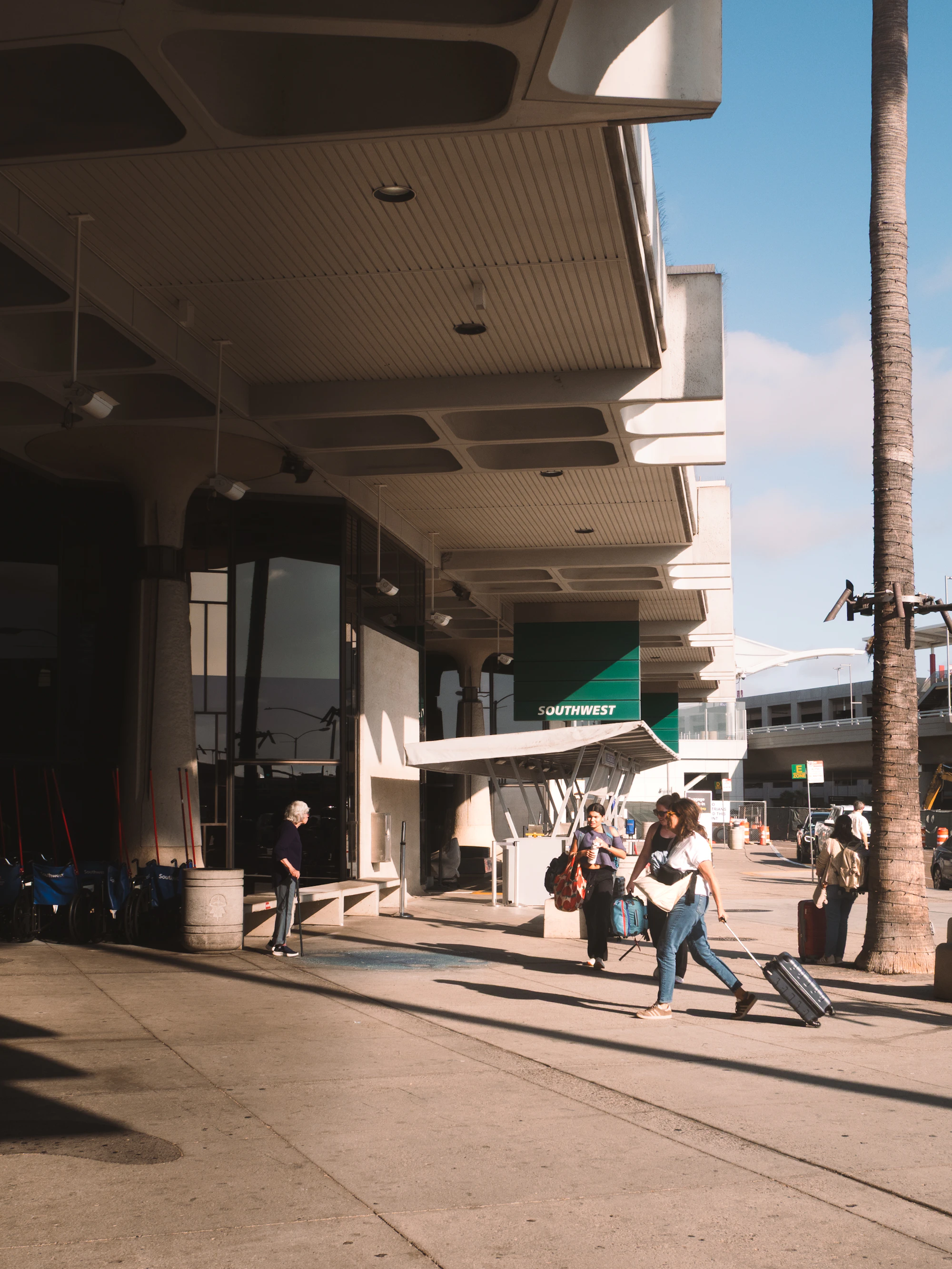 Travelers walking with suitcases outside an airport terminal