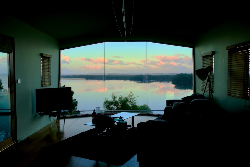 Living cu fereastră panoramică spre un lac, la apus
