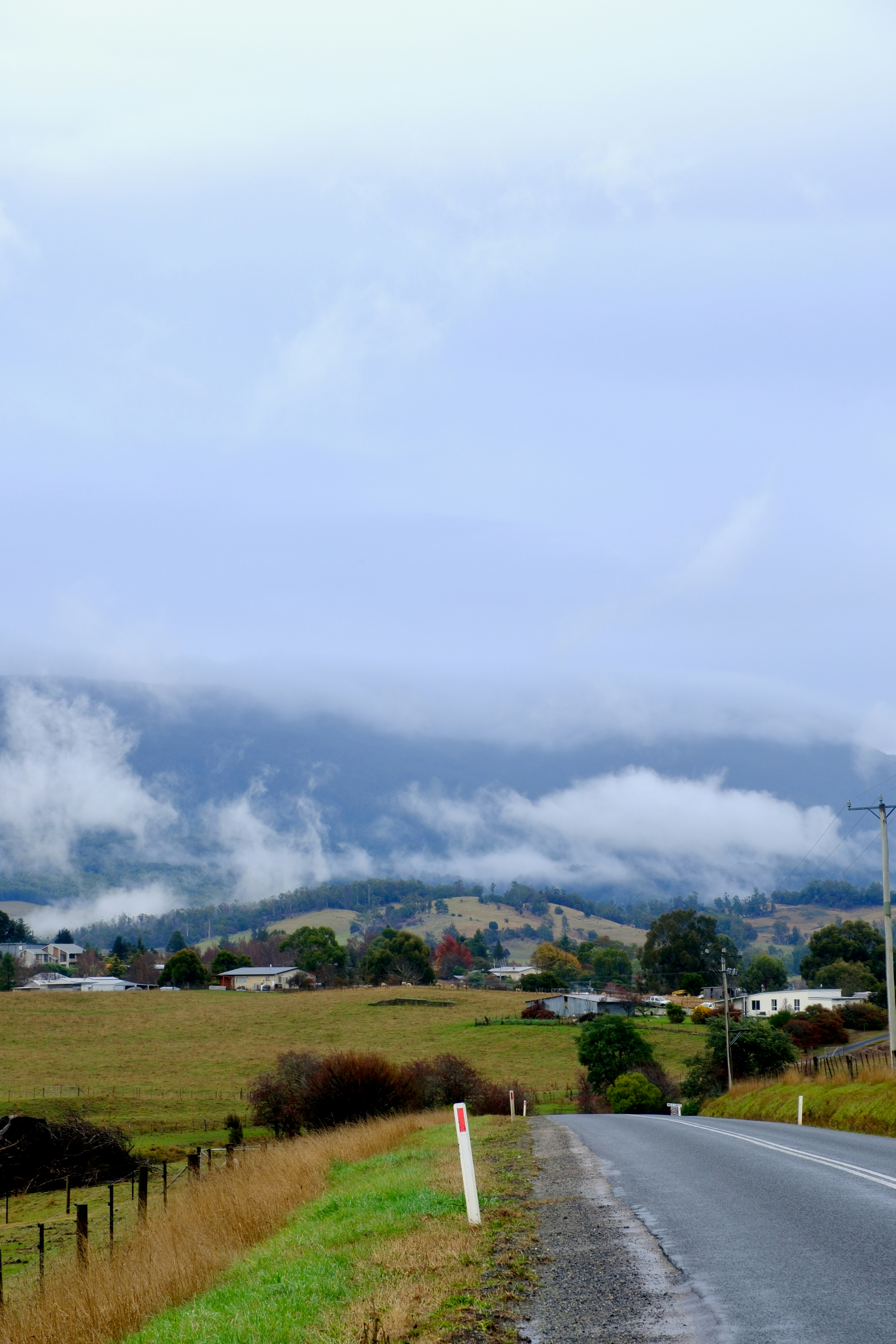 Carretera que conduce a un pueblo enclavado en colinas brumosas.