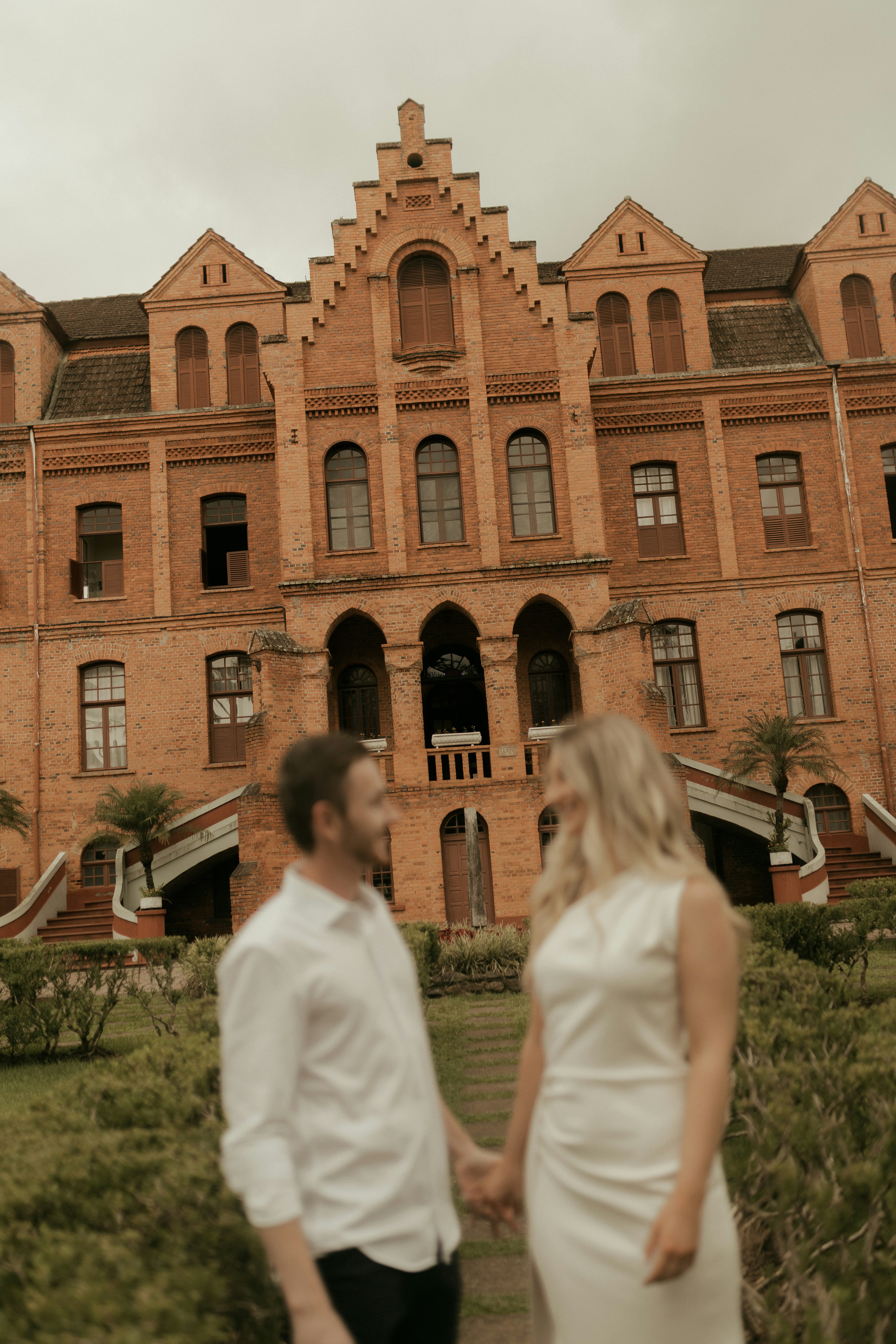 Couple holding hands in front of a brick building
