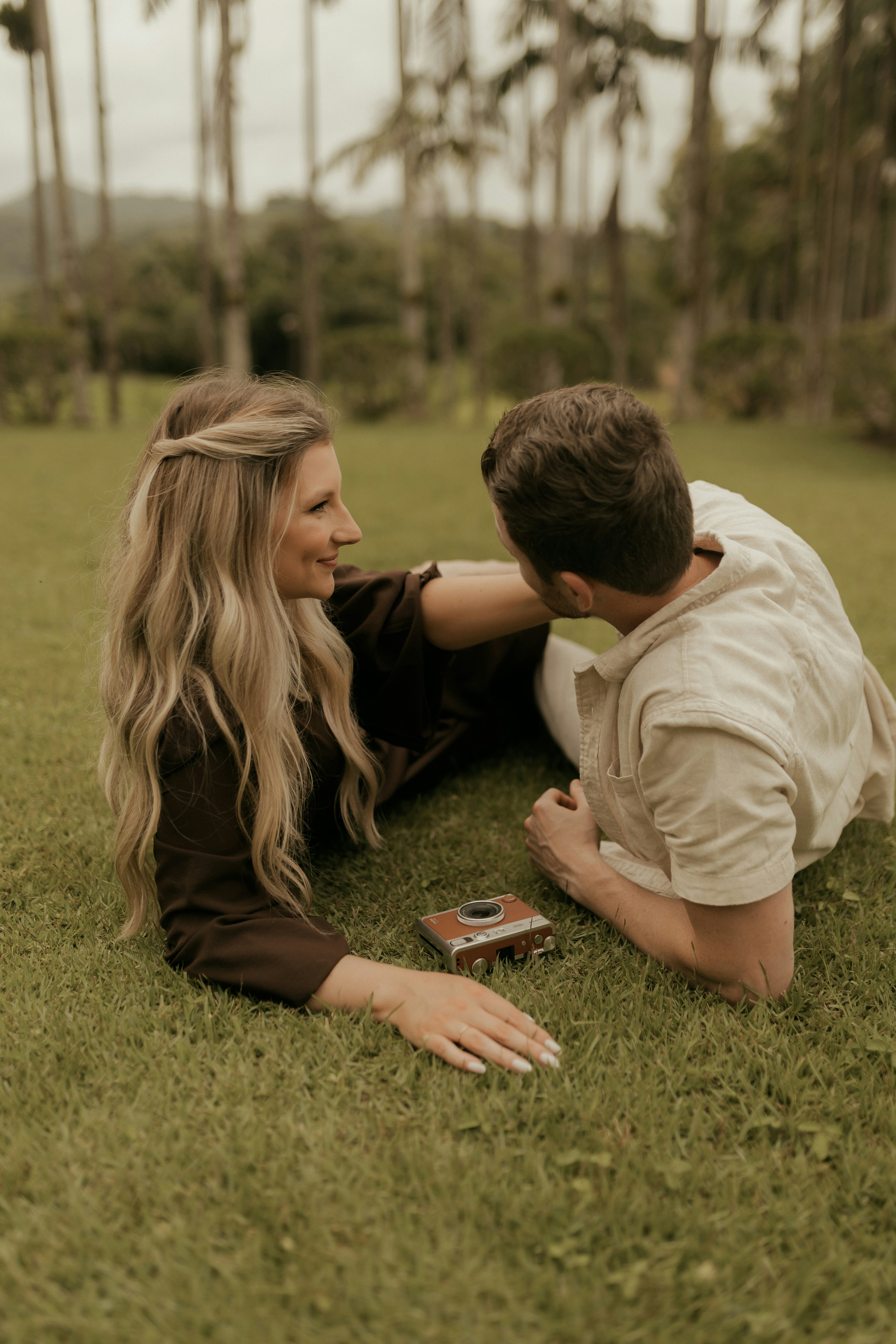 Paar liegt auf Gras mit einer Vintage-Kamera in der Nähe