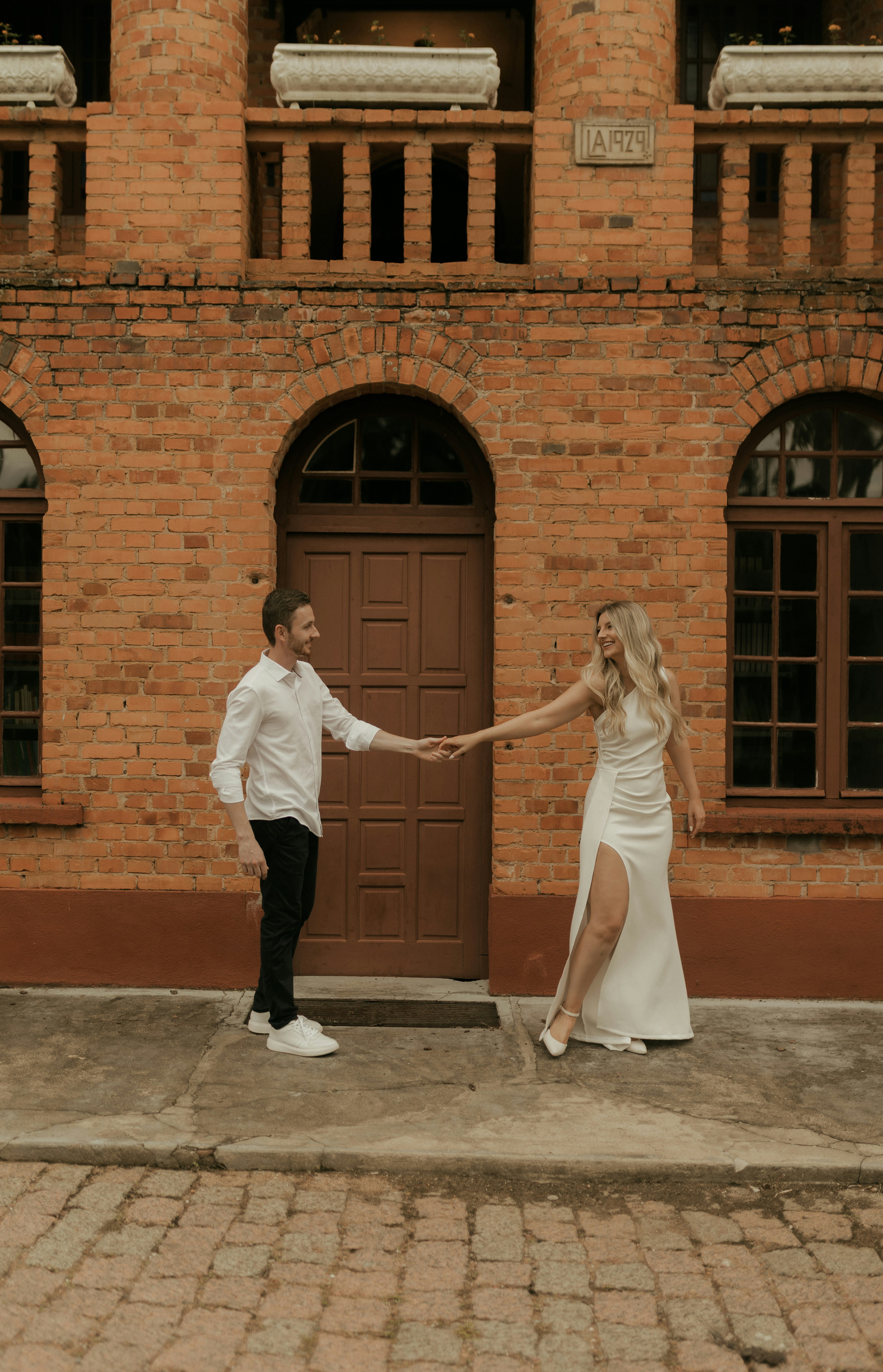 Couple holding hands in front of brick building