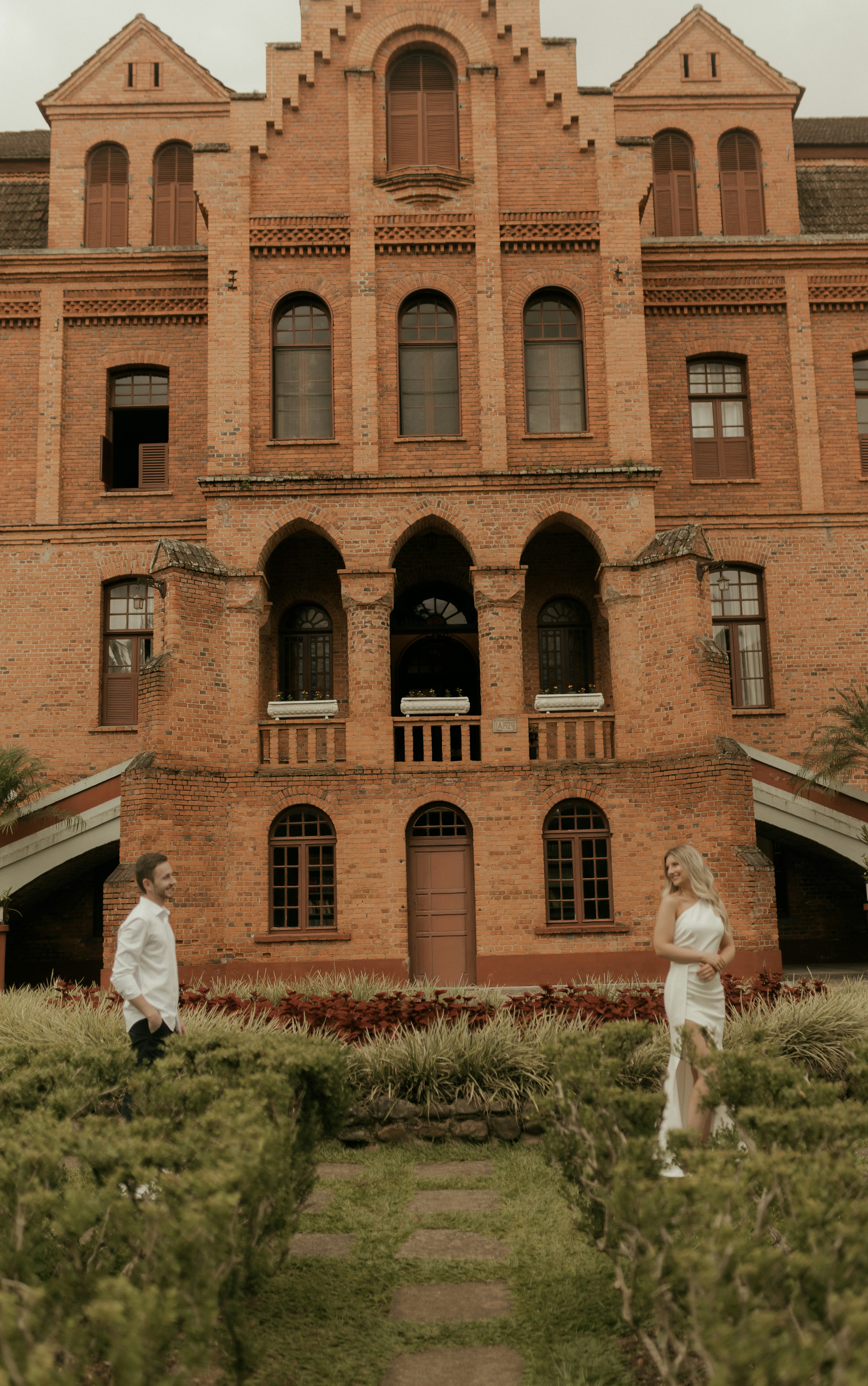 Couple in formal attire in front of a brick building