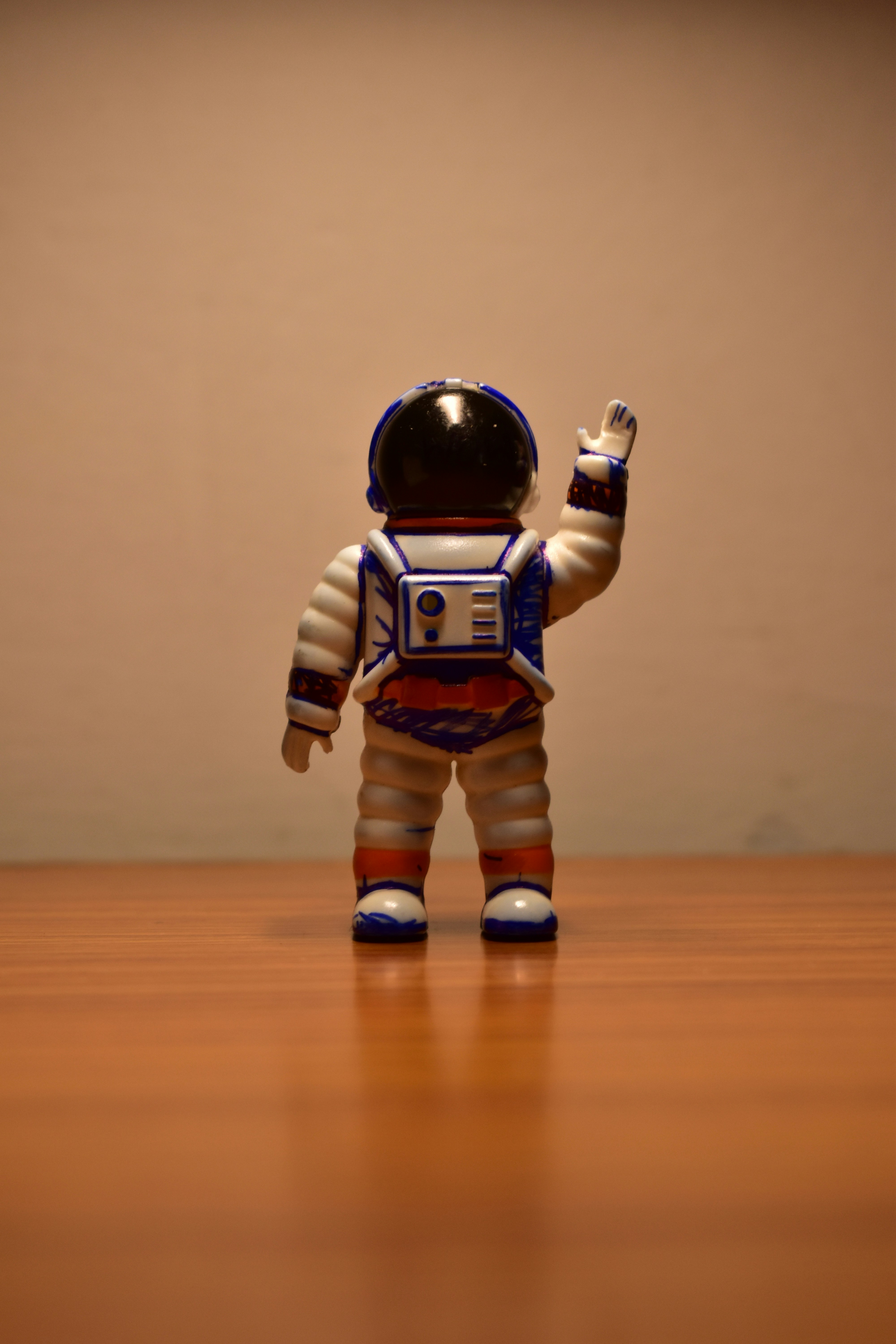 Astronaut toy waving hand on a wooden surface
