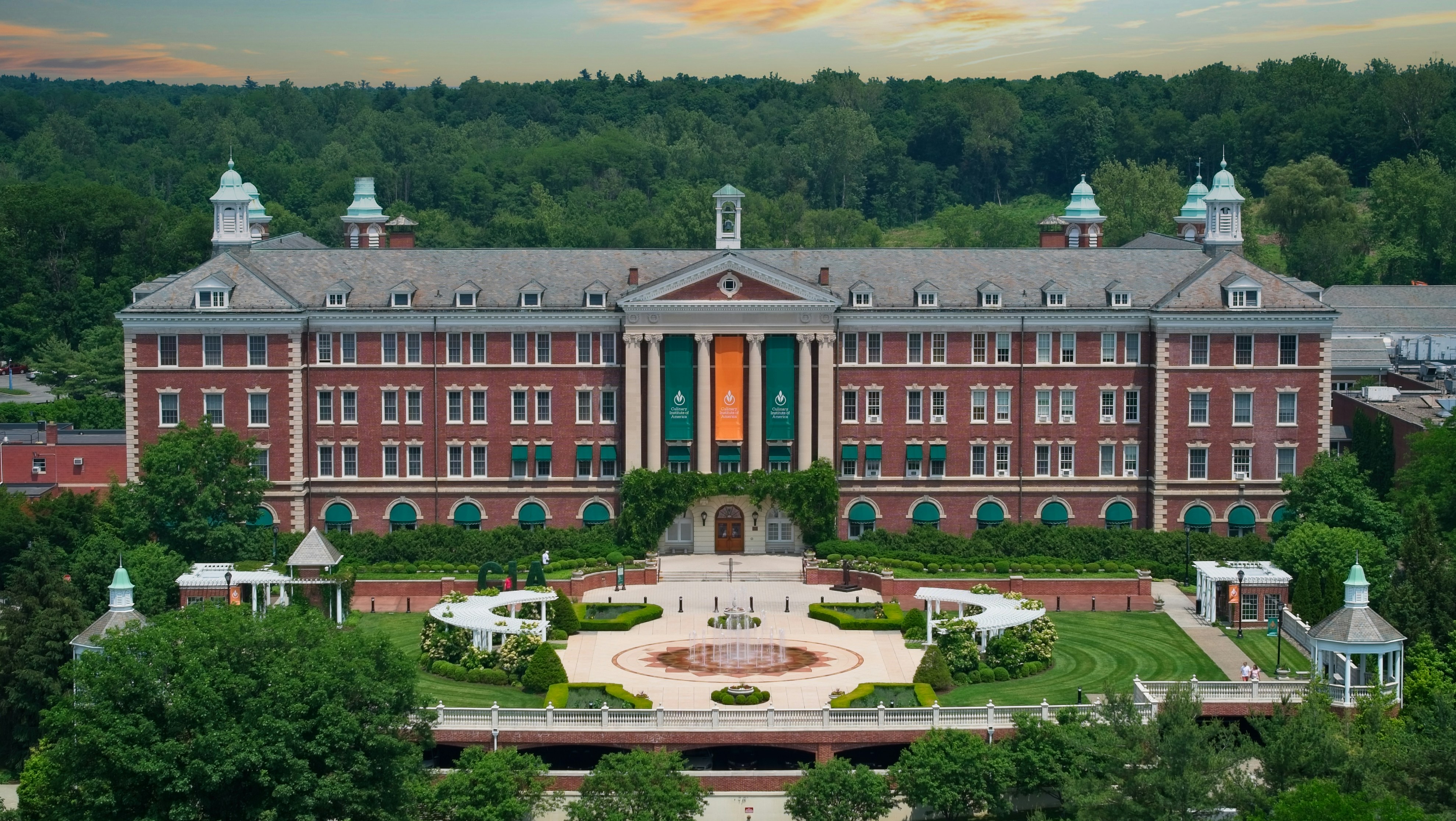 Grand brick building with manicured gardens and trees